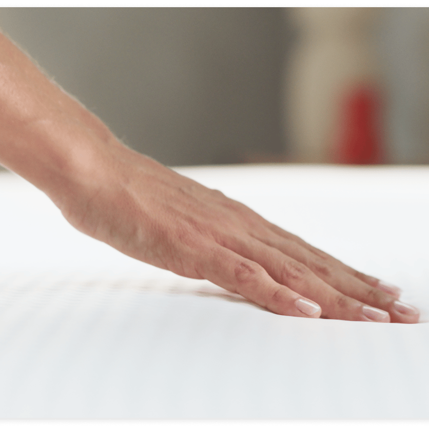 Hand berührt die Emma Matratze, zeigt Weichheit und Anpassungsfähigkeit.