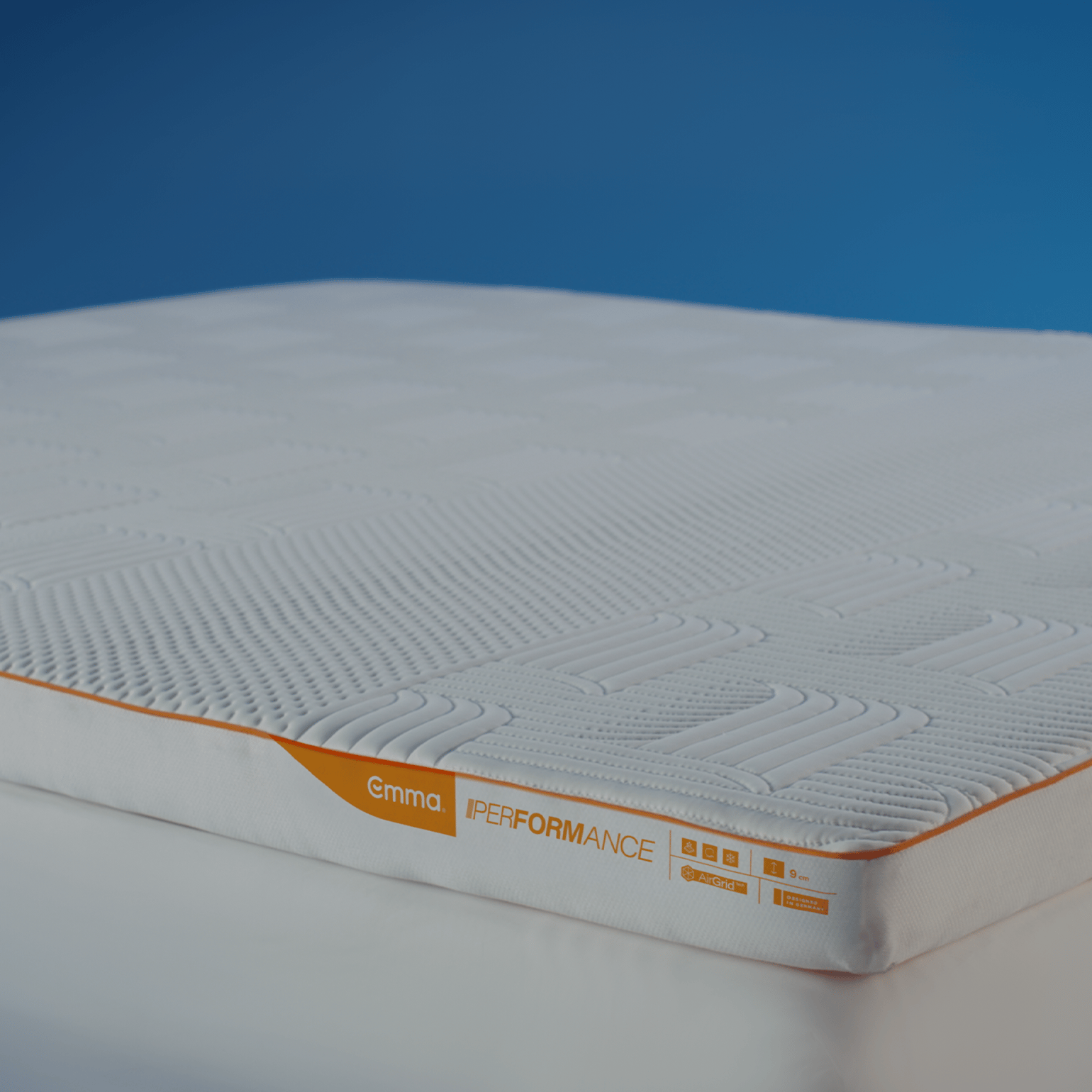 Emma Performance Topper standalone product shot showing quilted white surface and orange stripe with Emma Performance label.
