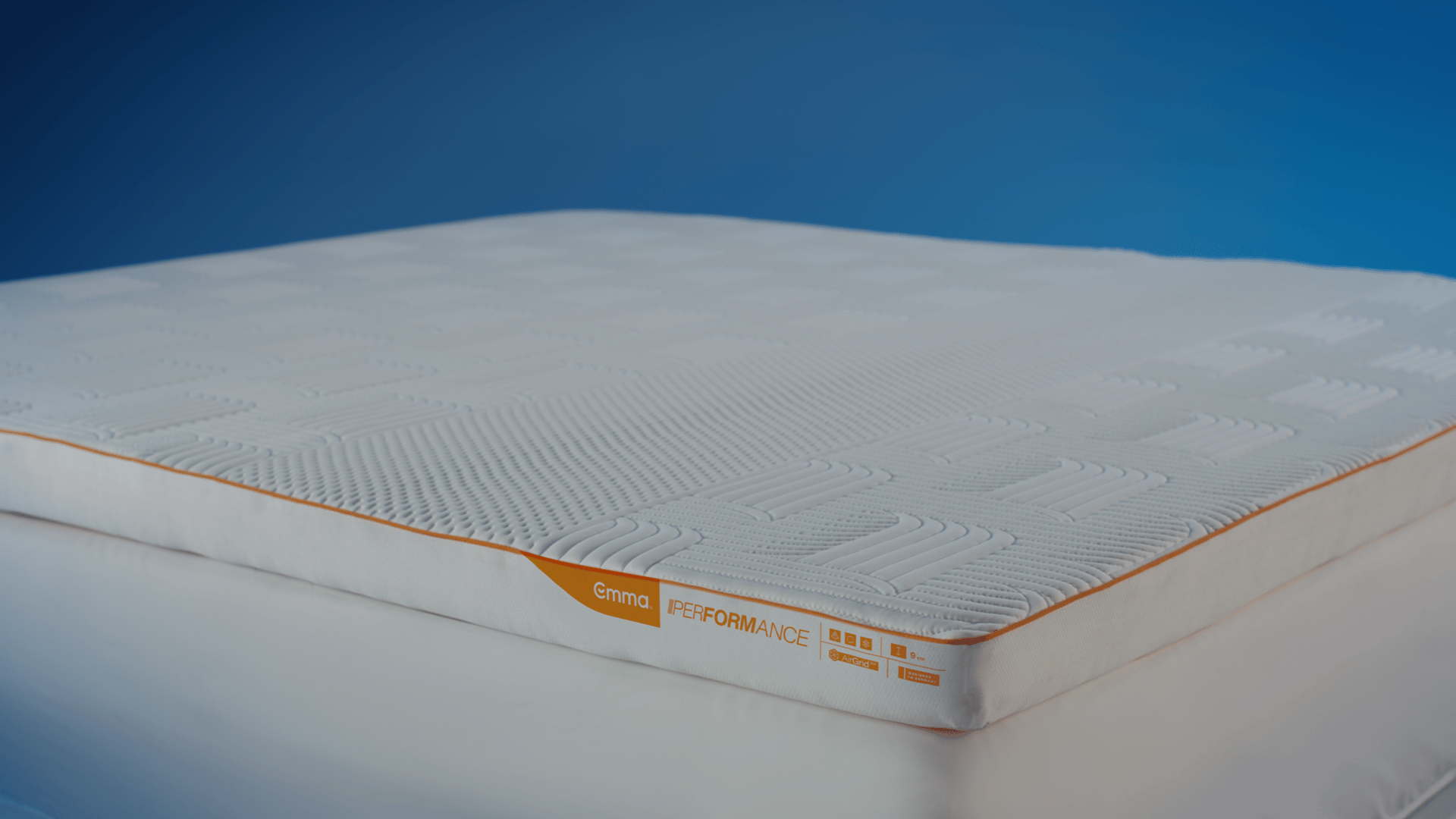 Emma Performance Topper standalone product shot showing quilted white surface and orange stripe with Emma Performance label.