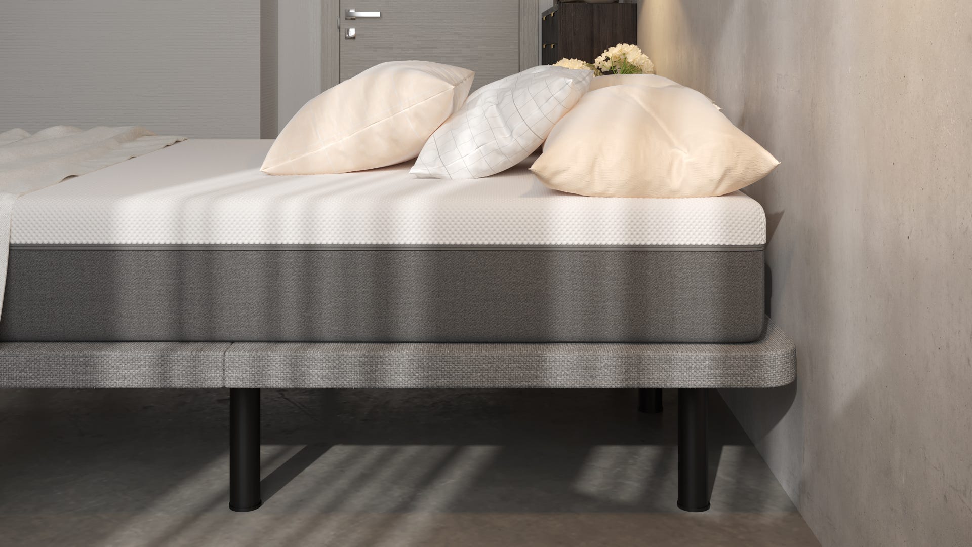 base de cama tapizadacon colchon y almohadas en una habitaciñon con paredes grises