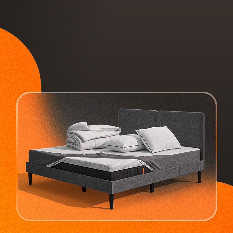 Lit moderne avec tête de lit grise et pieds noirs, recouvert de draps blancs. Deux oreillers blancs et une pile de linge plié sont posés sur le matelas. Arrière-plan beige avec une forme orange abstraite.