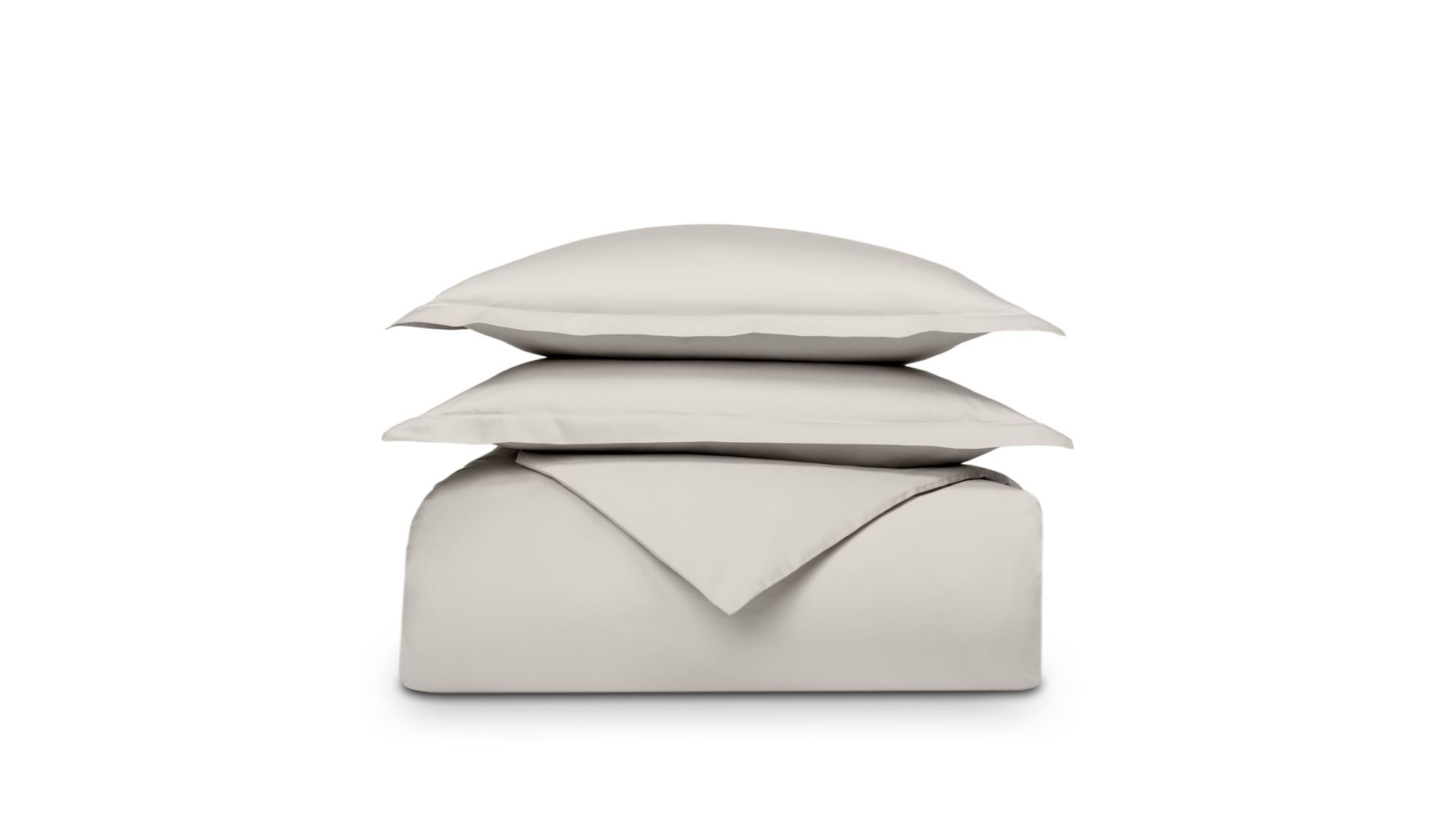 Set di biancheria piegato beige su sfondo bianco, cuscino sopra il piumone.