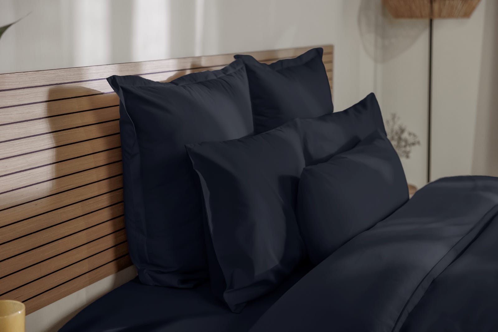 Uma imagem de almofadas numa cama composta, com fronhas de almofada Emma cinzentas escuras