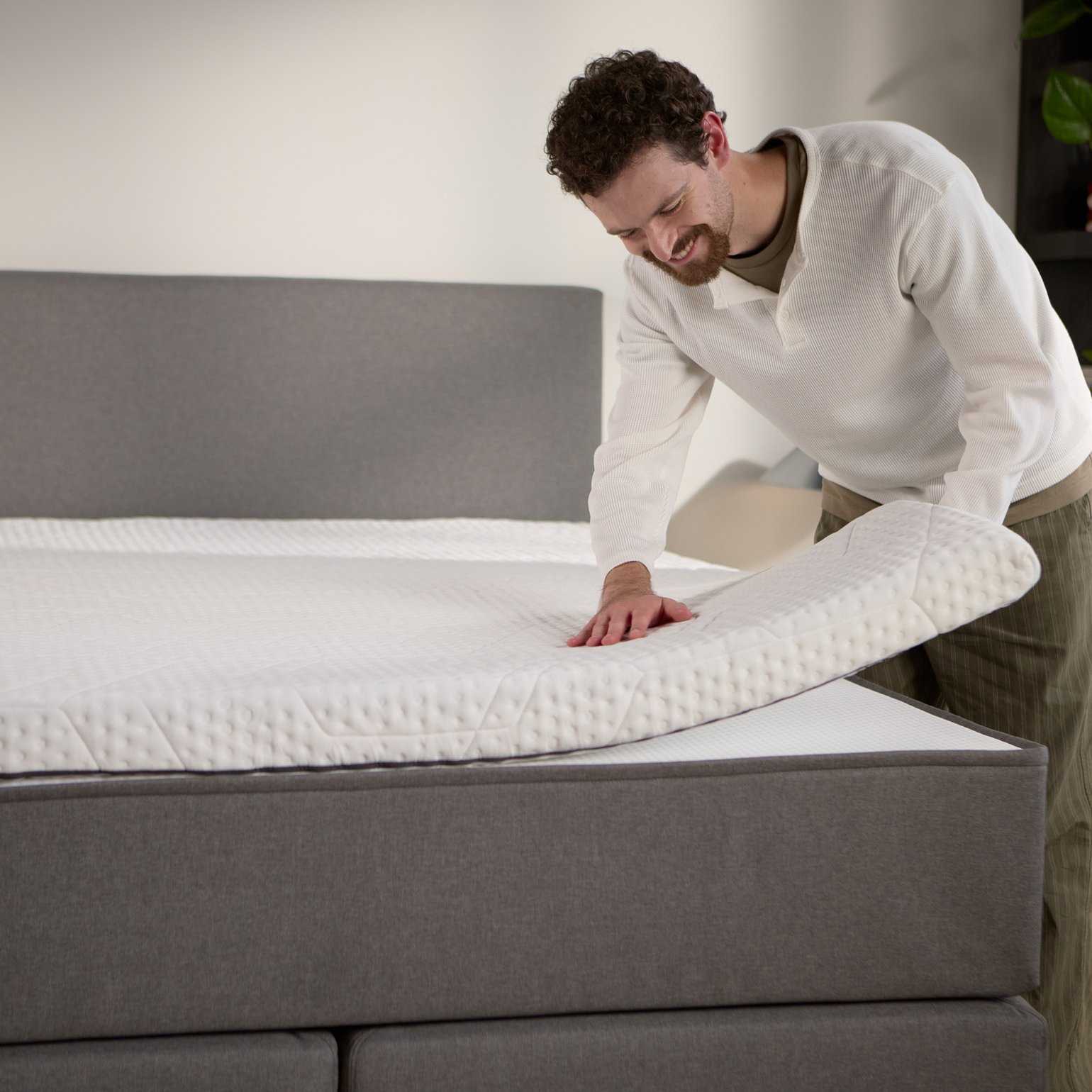 Detailaanzicht van een losse matrastopper die op het boxspringbed wordt opgetild, met extra comfort aan de bovenkant.