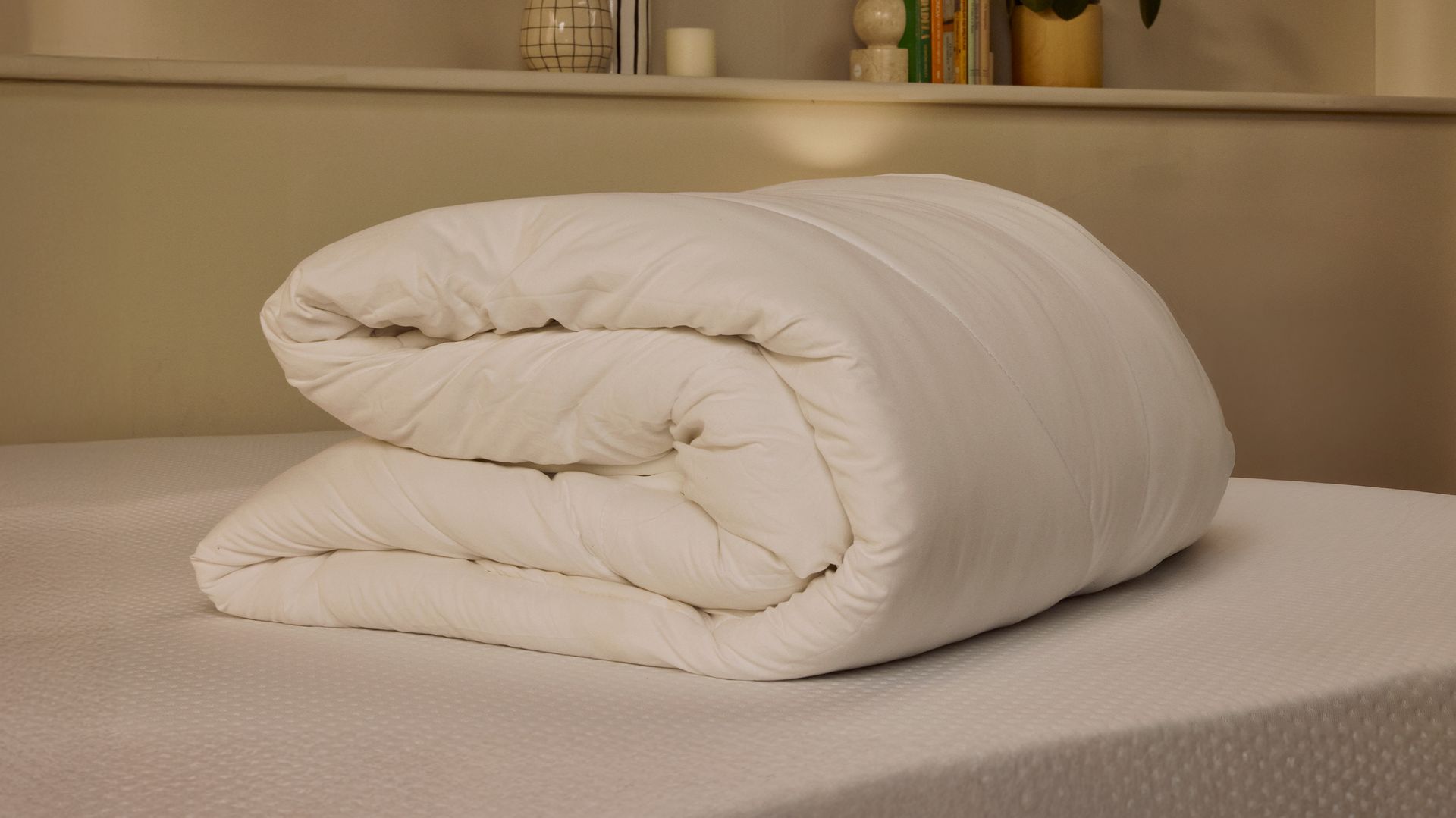 Folded duvet on top of a mattress.