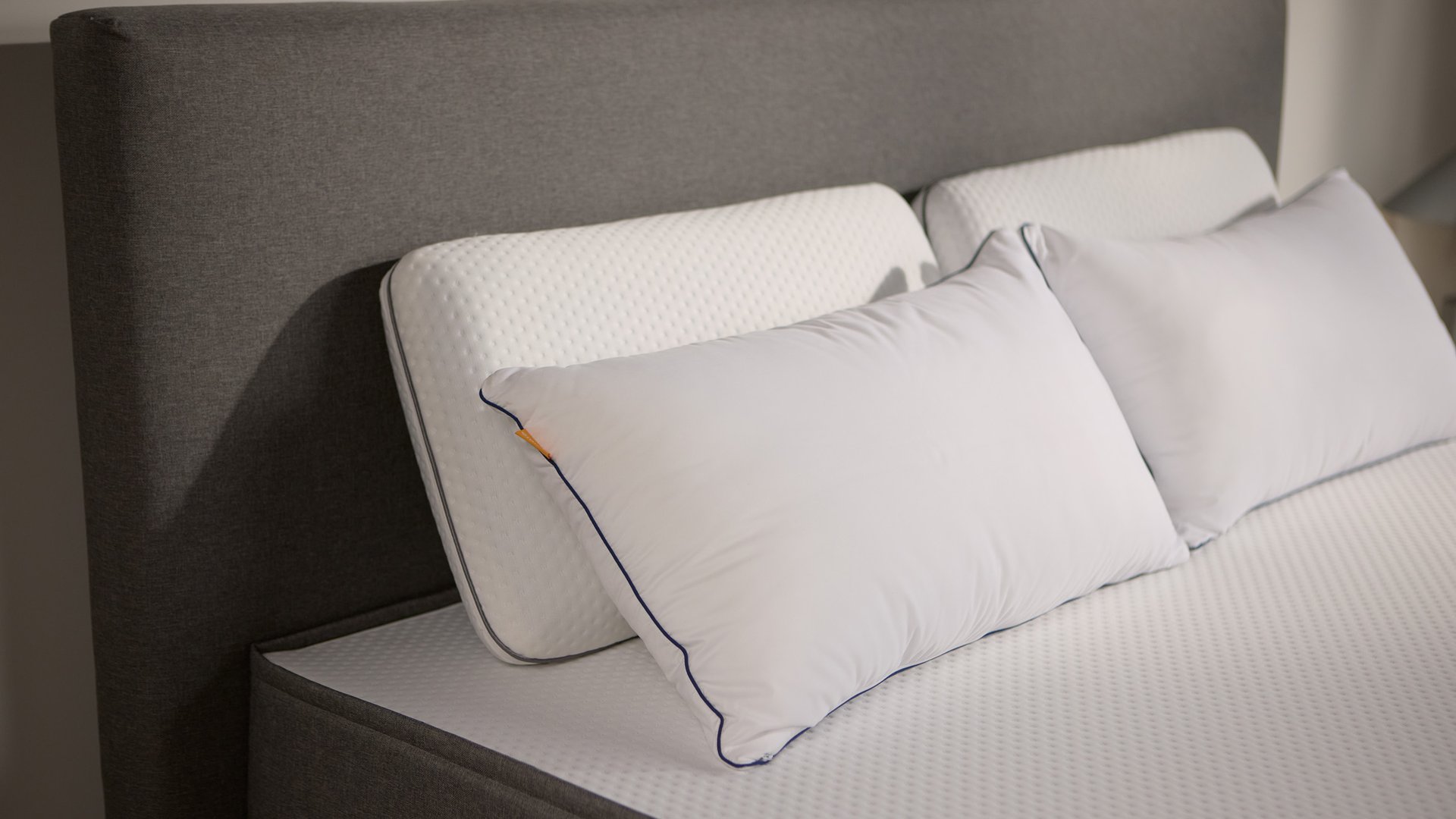 Nahaufnahme des dunkelgrau stoffbezogenen Bettrahmens mit zwei Paar Emma Polster aus Schaum und Mikrofaser.