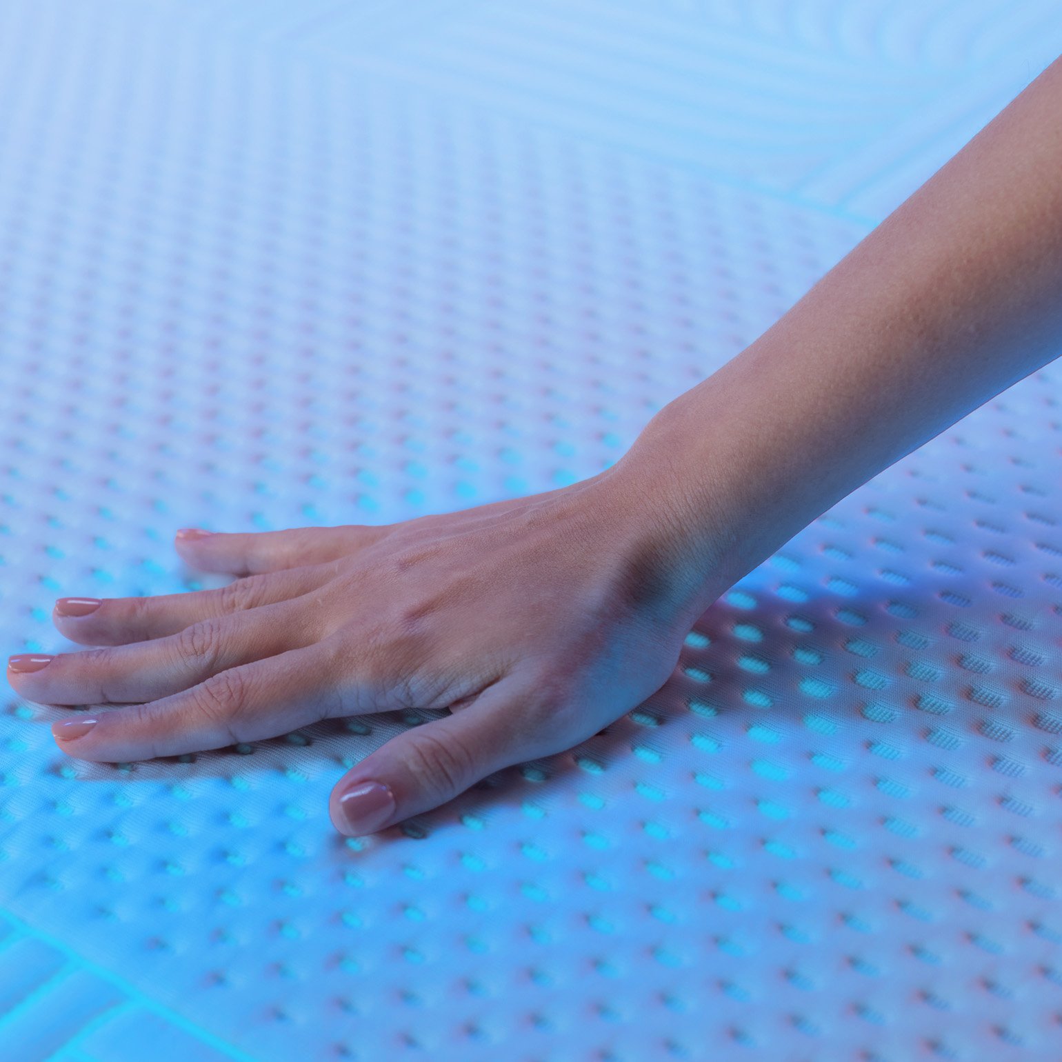 Hand pressing Emma Performance mattress cover showing breathable, cushioned surface.