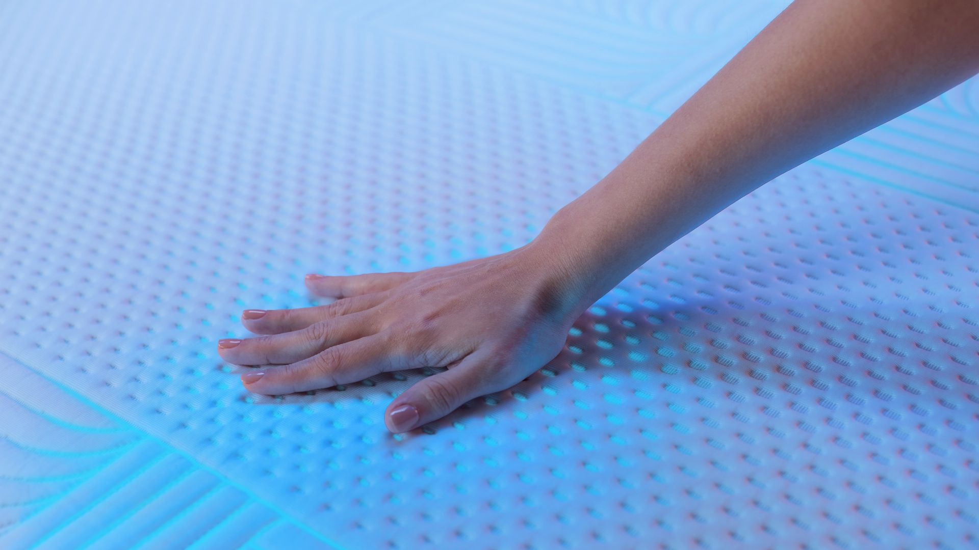 Hand pressing Emma Performance mattress cover showing breathable, cushioned surface.