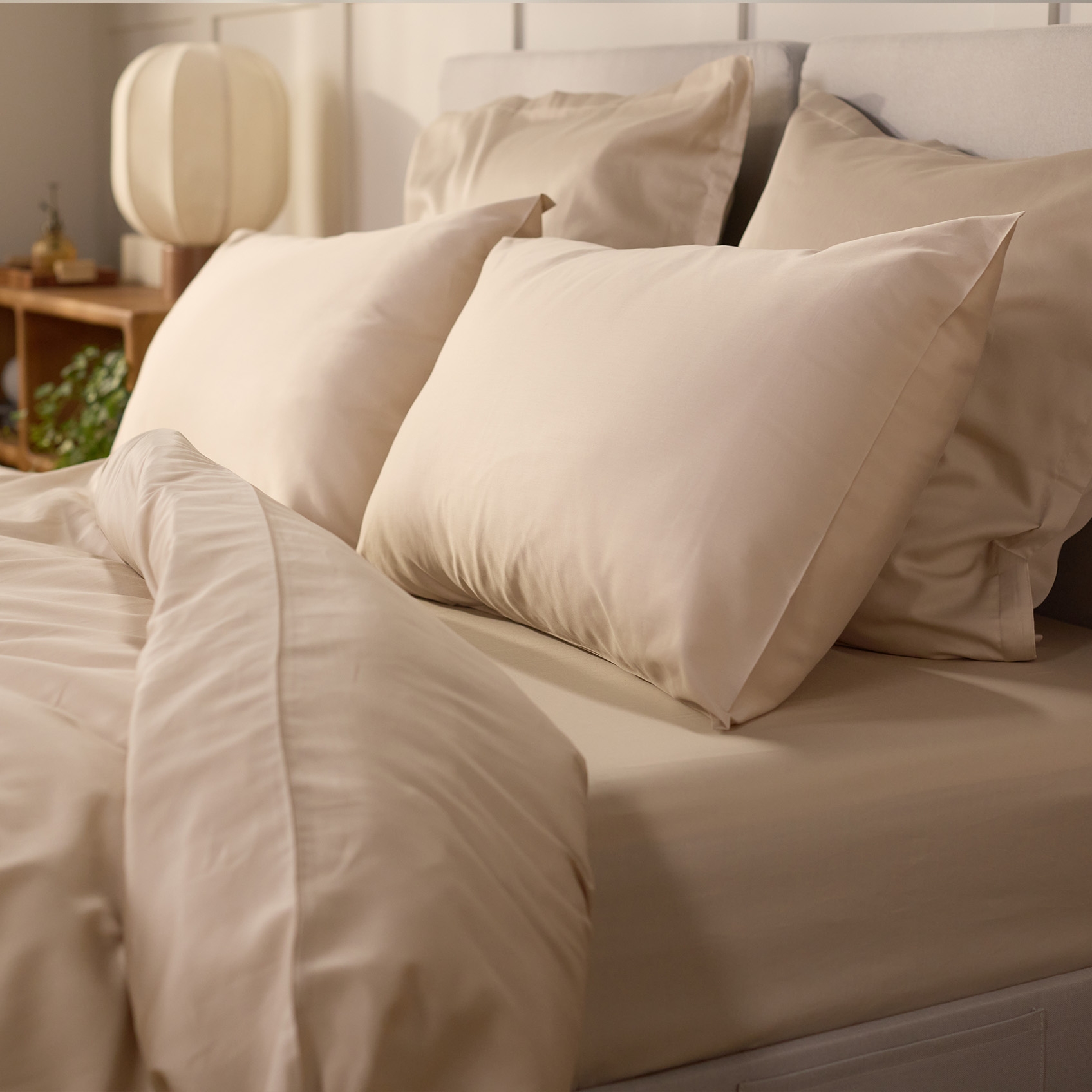 Image en gros plan d’un lit avec une housse de couette et quatre oreillers.