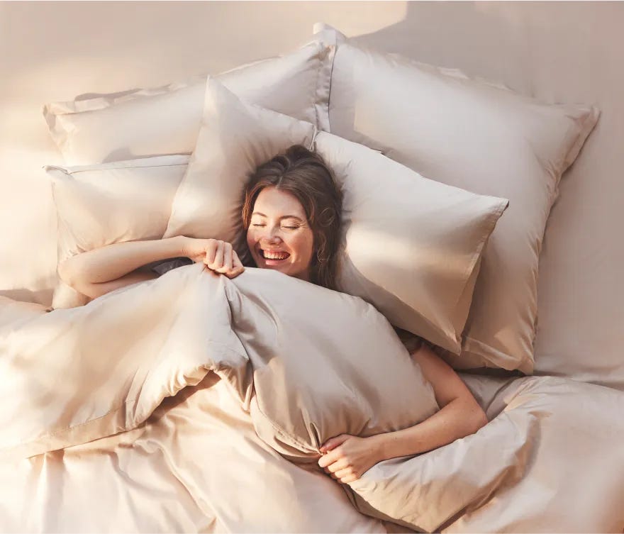 Persona a letto coperta da cuscini e coperte.