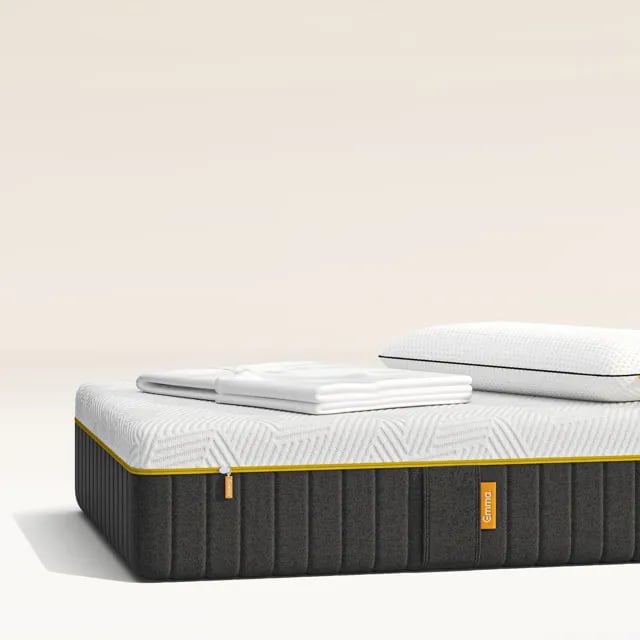 Emma Schlafset mit Boxspringbett, Matratzenschöner und Kissen in modernem Schlafzimmer.