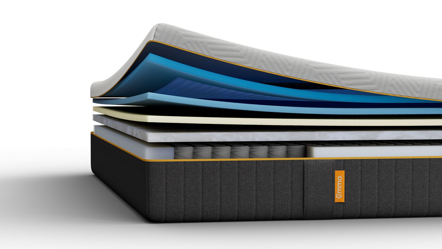 Lit tapissé gris avec matelas blanc, dans une chambre.