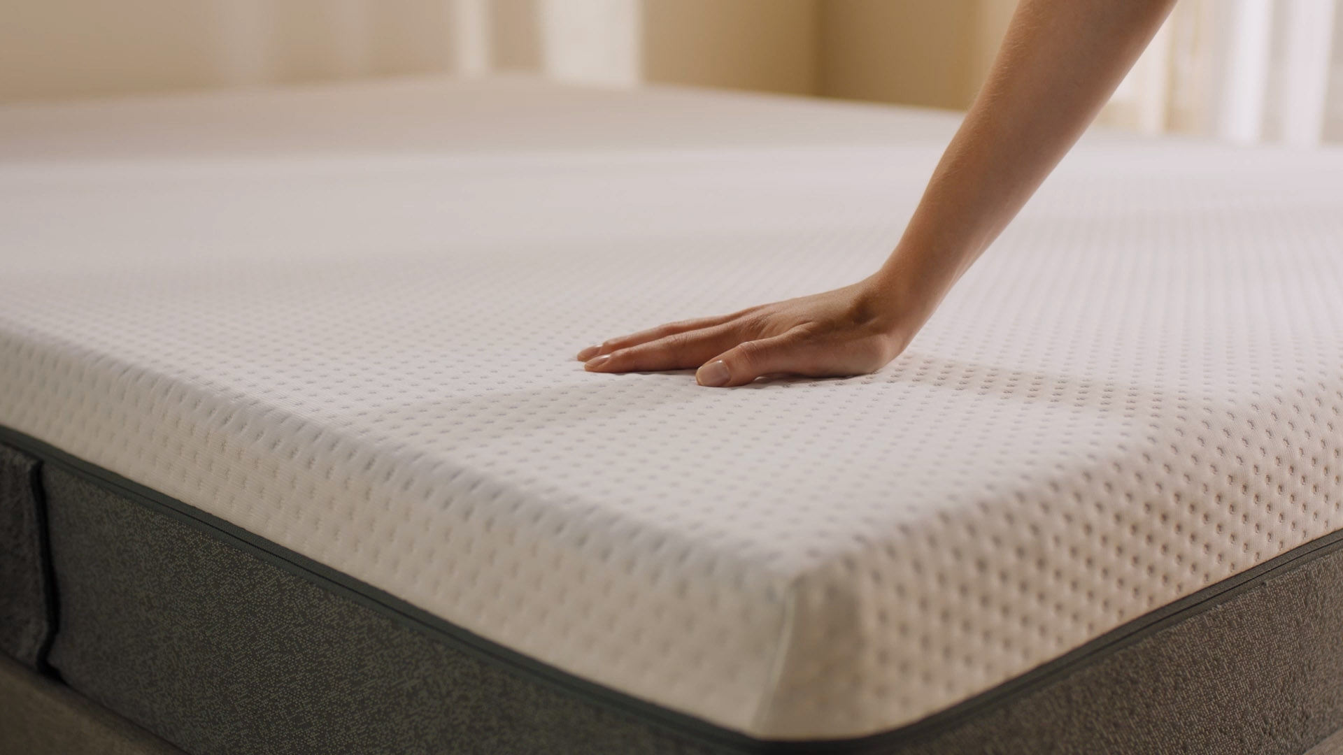 Person pressing the mattress surface to show its feel.