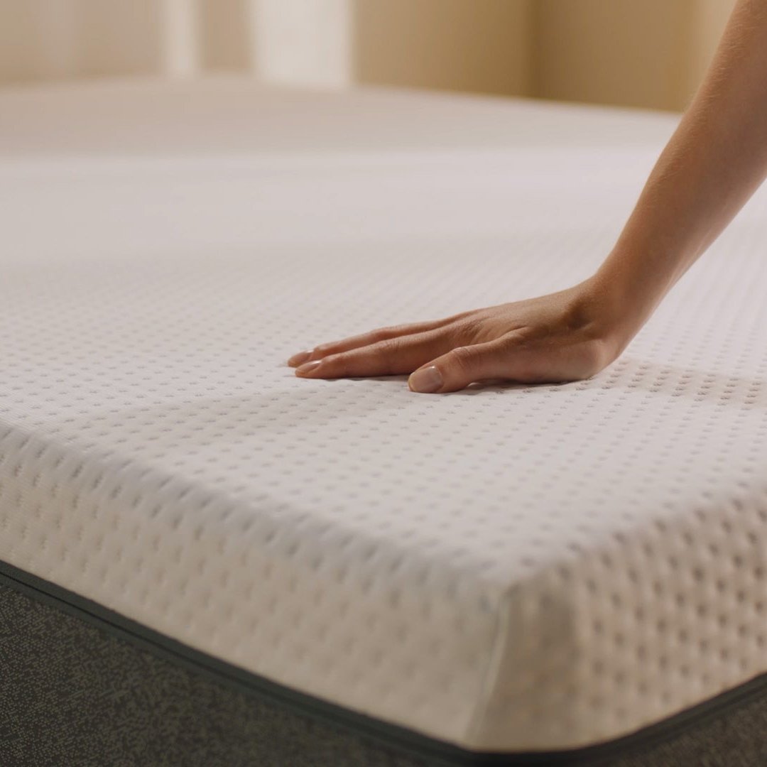 Person pressing the mattress surface to show its feel.