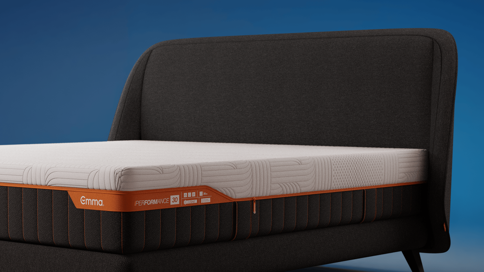 Emma Performance boxspringbed with charcoal upholstered curved headboard, matching base, and black tapered legs.