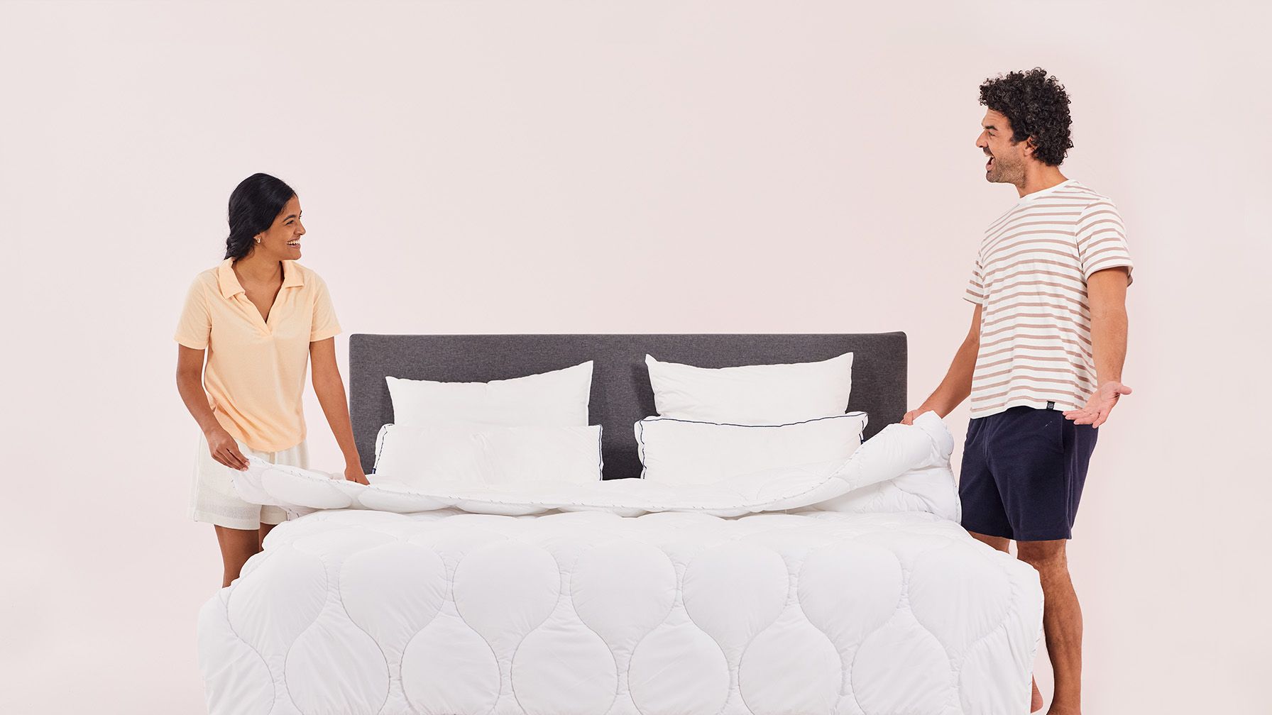 Paar macht Bett mit weißer Emma Bettdecke.