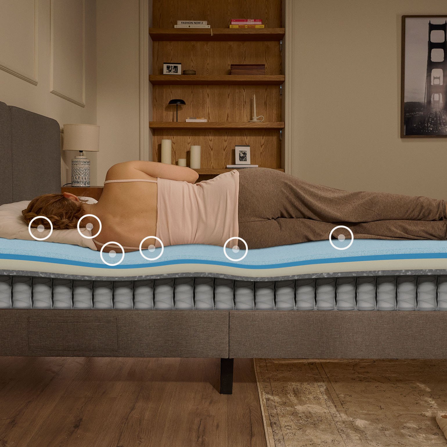 Woman sleeping on her side on an Emma Original Pro mattress with a layers view showing foam and spring construction beneath her.
