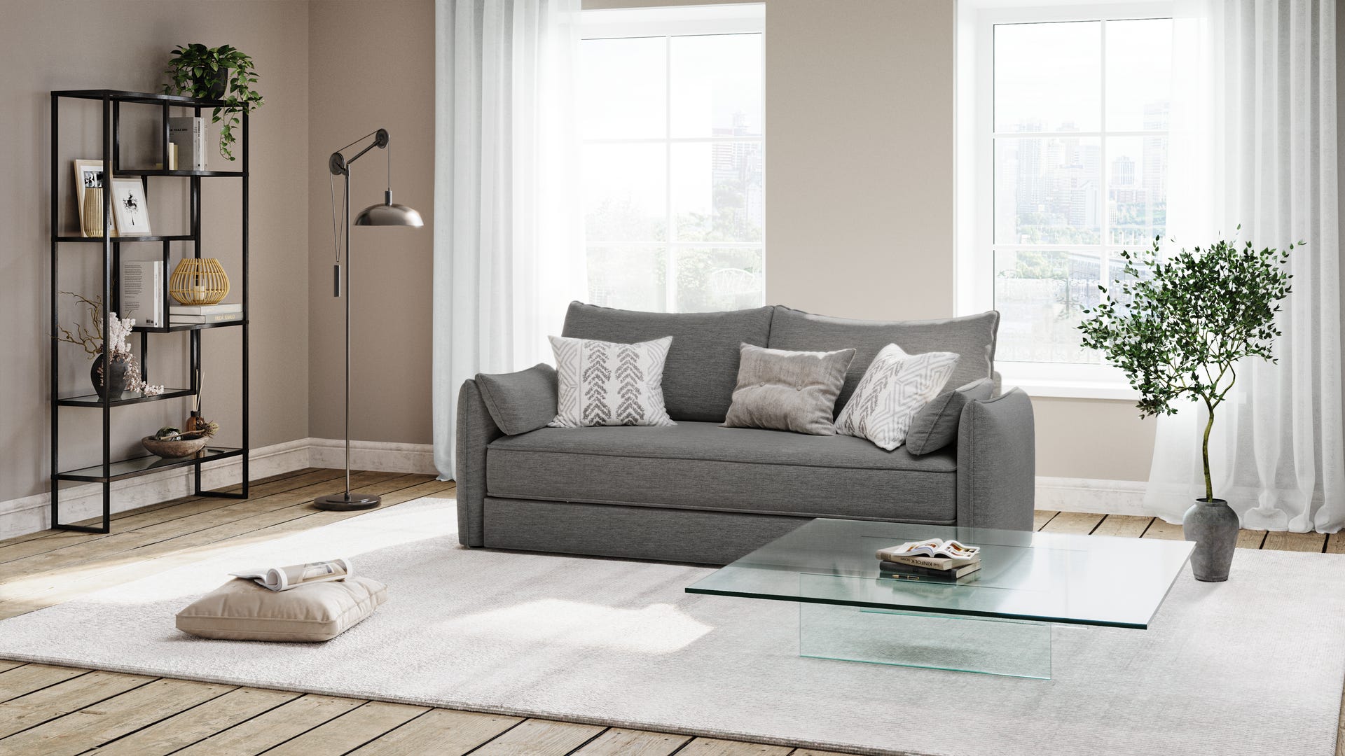Canapé convertible gris avec plusieurs coussins décoratifs blancs et gris, placé sur un tapis blanc dans un salon lumineux. Devant le canapé, table basse en verre avec un livre posé dessus. Deux coussins de sol beiges sur le tapis. À gauche, étagère en métal noir avec vases, livres et plantes. Lampadaire métallique à côté. À droite, plante verte près de deux grandes fenêtres avec rideaux blancs. Ambiance cosy, minimaliste et bien agencée.