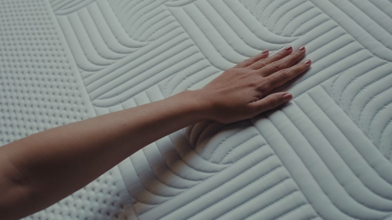Hand gliding across a cool touch textured mattress surface, highlighting softness and temperature regulation.