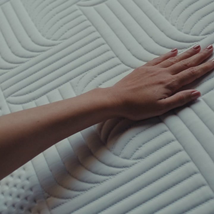 Hand gliding across a cool touch textured mattress surface, highlighting softness and temperature regulation.