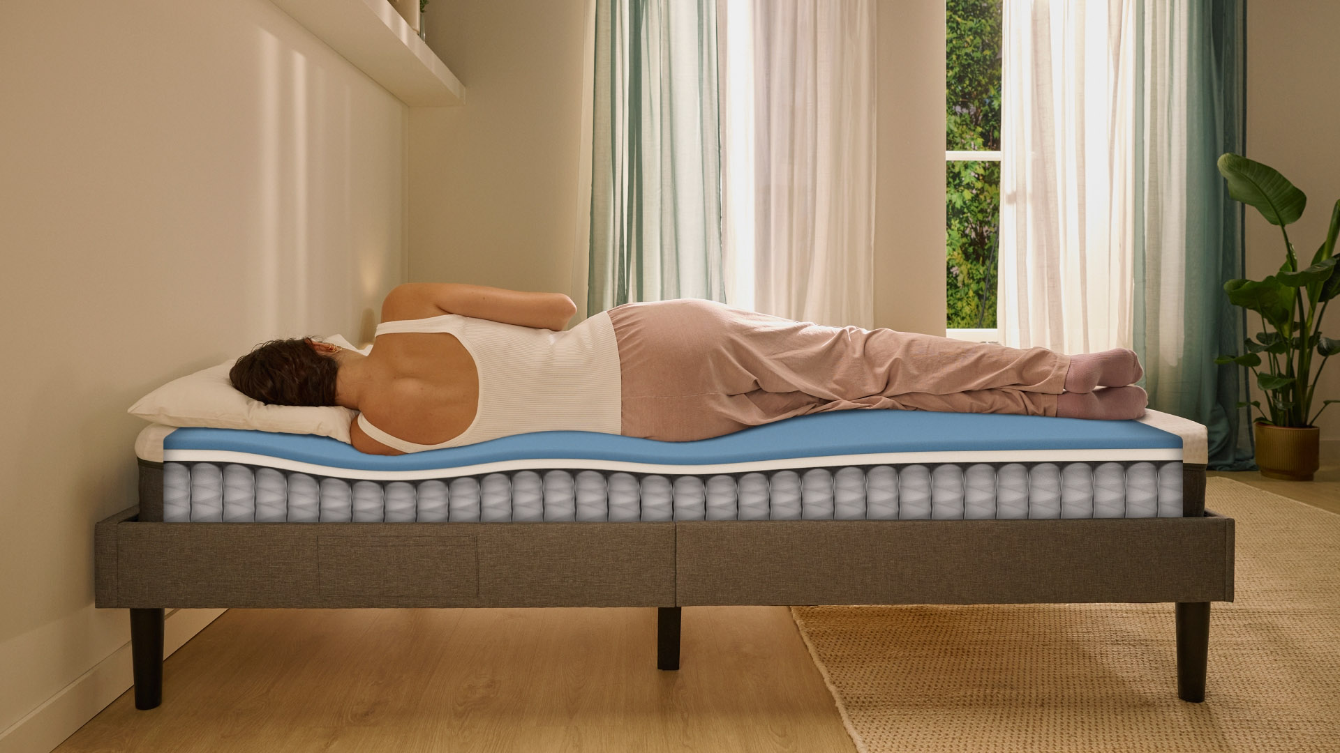 Person lying on their side on a white mattress in a relaxed sleeping position.