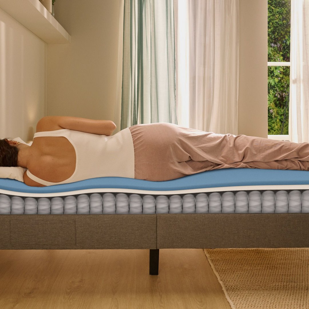 Person lying on their side on a white mattress in a relaxed sleeping position.