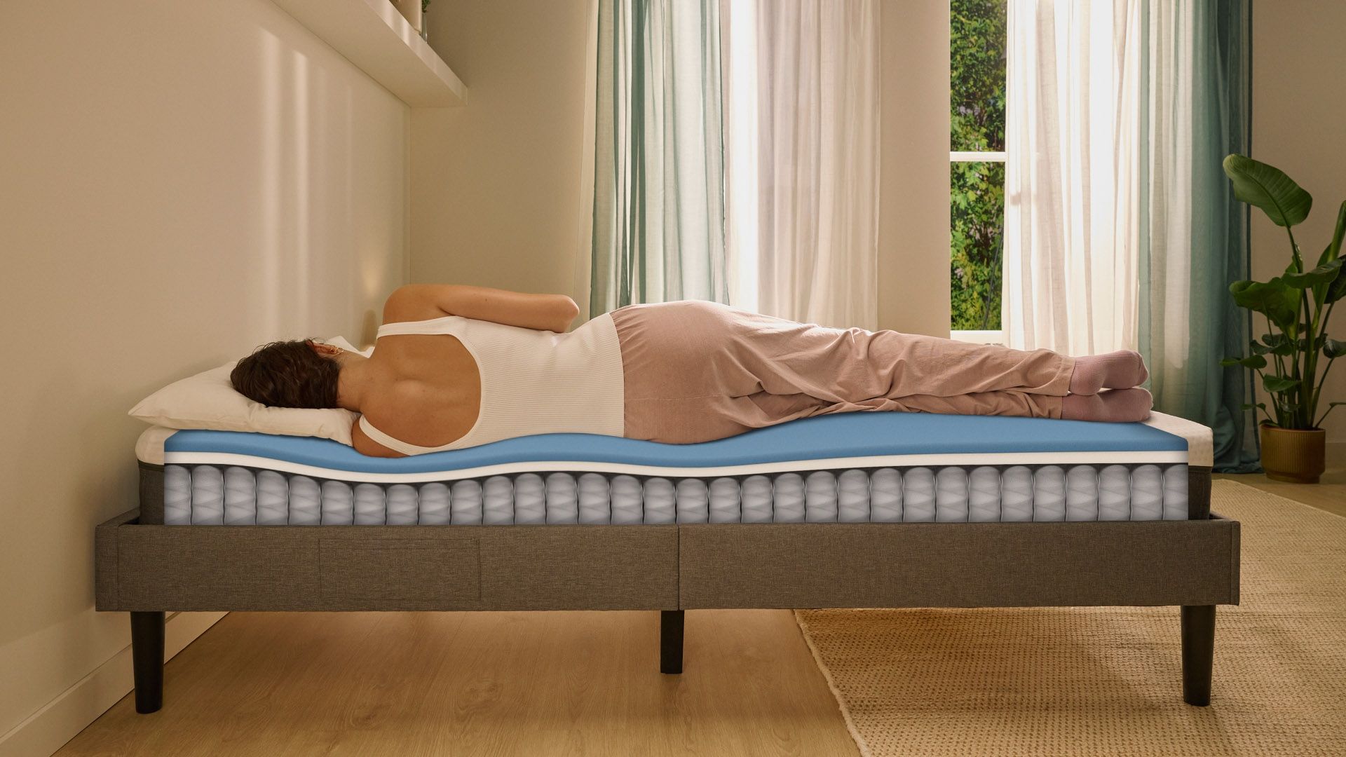 Person lying on their side on a white mattress in a relaxed sleeping position.