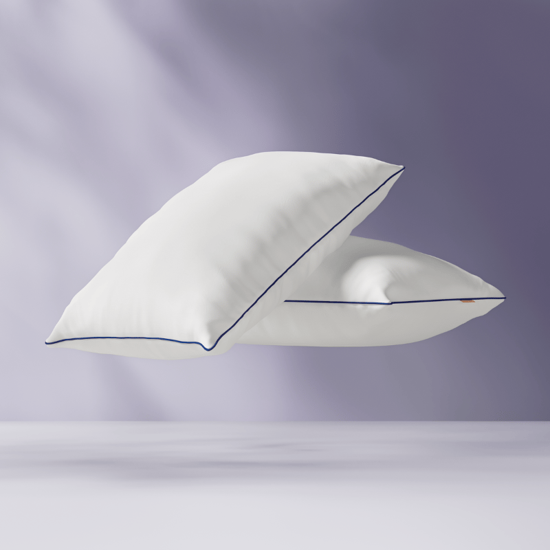 Deux oreillers flottants avec une bande bleue, sur un fond violet clair.