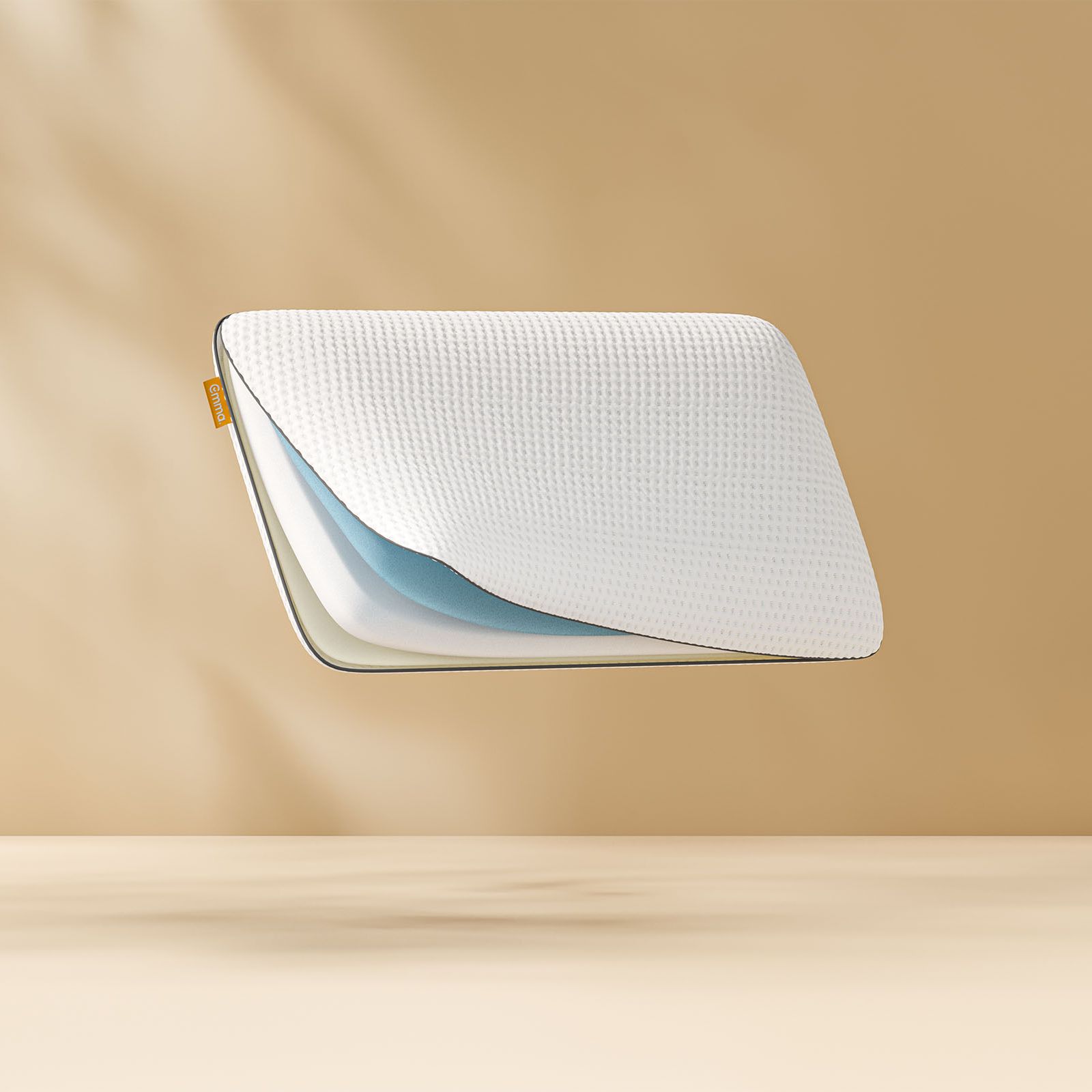 Oreiller flottant montrant ses couches de mousse internes avec un logo Emma. Fond bronze clair.