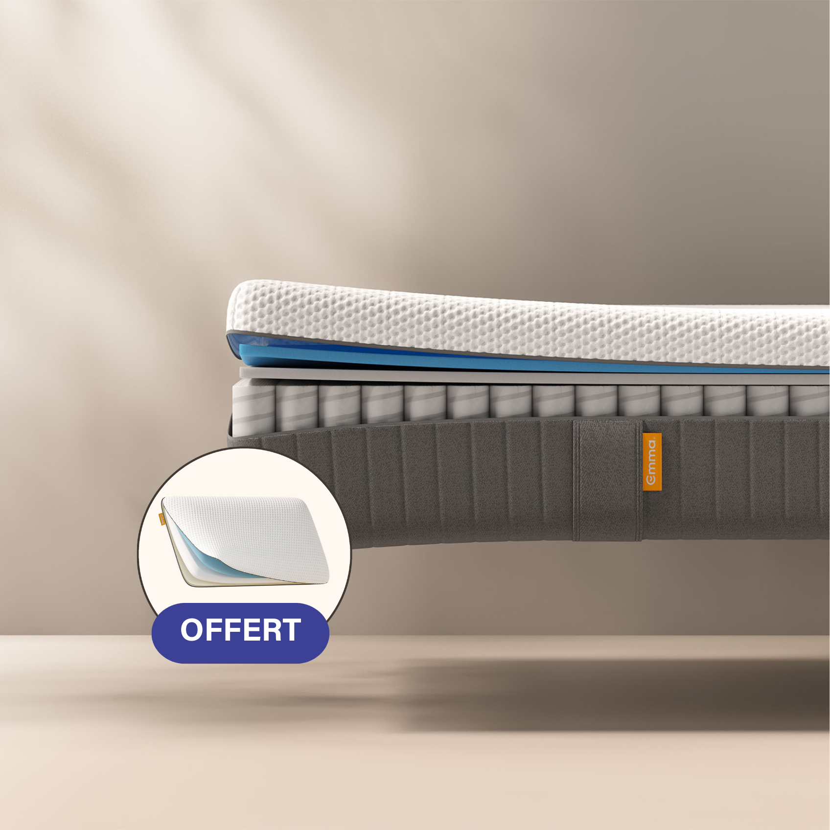 Coupe transversale d'un matelas montrant plusieurs couches, dont une couche supérieure texturée blanche, des couches intermédiaires bleues et jaunes, et un sommier dont les ressorts sont visibles. Le matelas porte l'inscription "Emma" sur le côté.