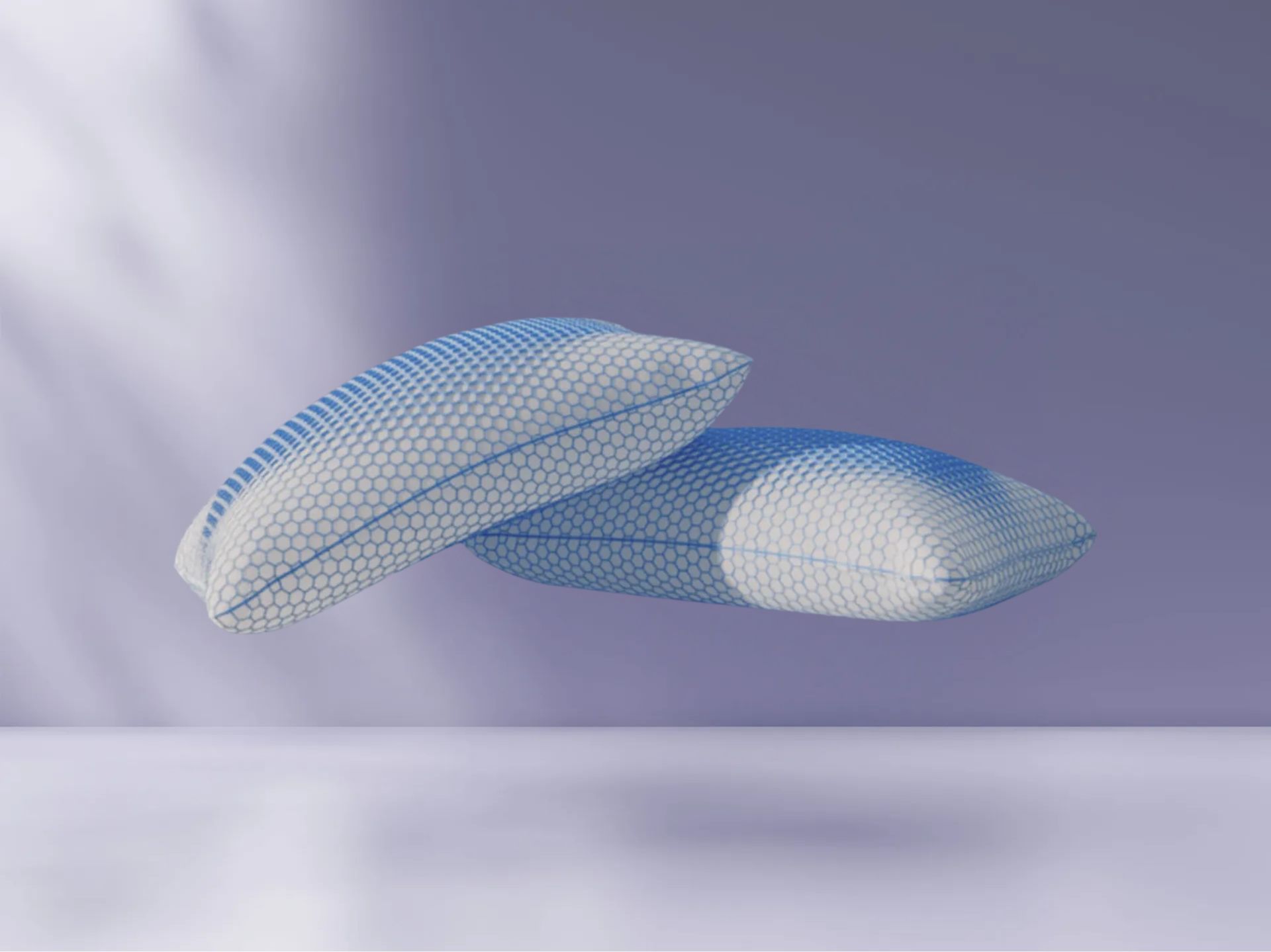 Twee AirGrid® Comfort Kussens met witte hoes en blauwe honingraatpatroon, zwevend tegen een zachte paarse achtergrond.