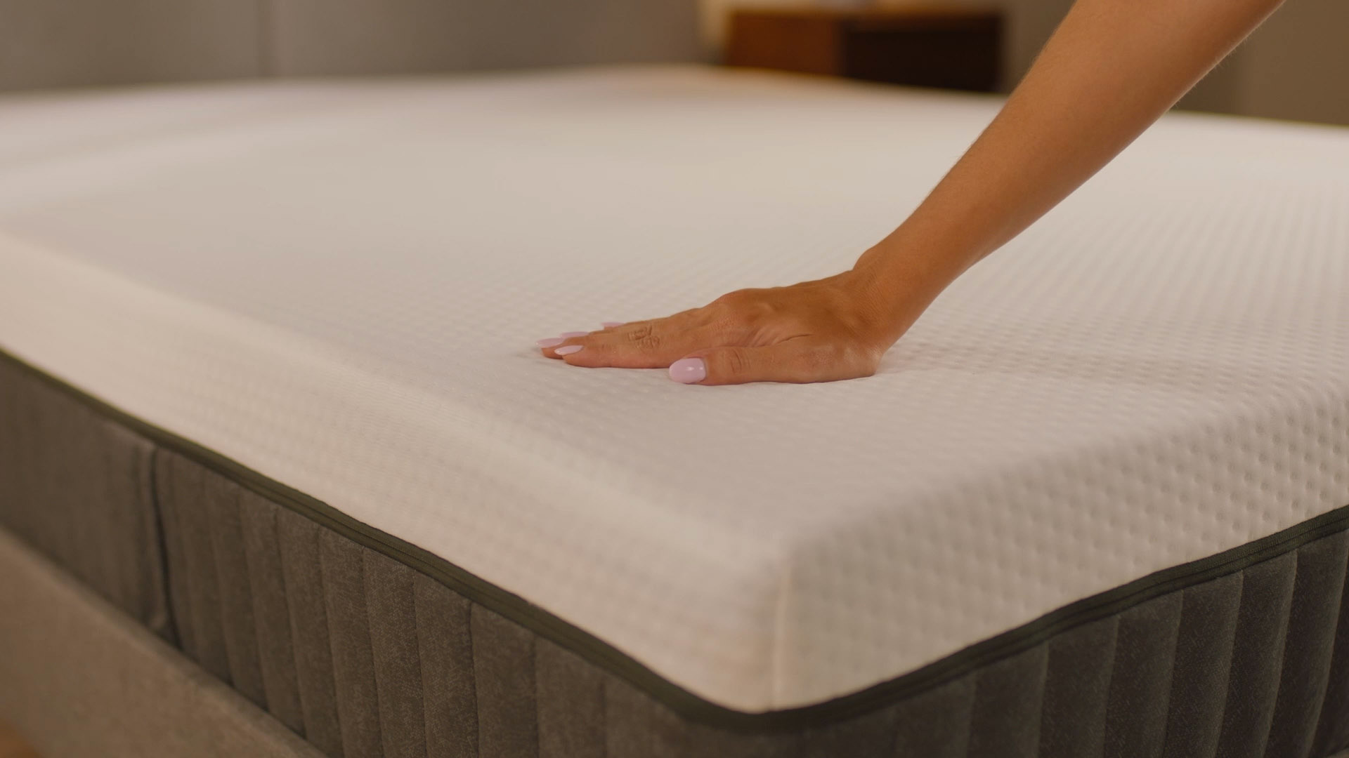 Main appuyant légèrement sur la surface d’un matelas en mousse premium pour illustrer son confort, son soutien et sa réactivité.