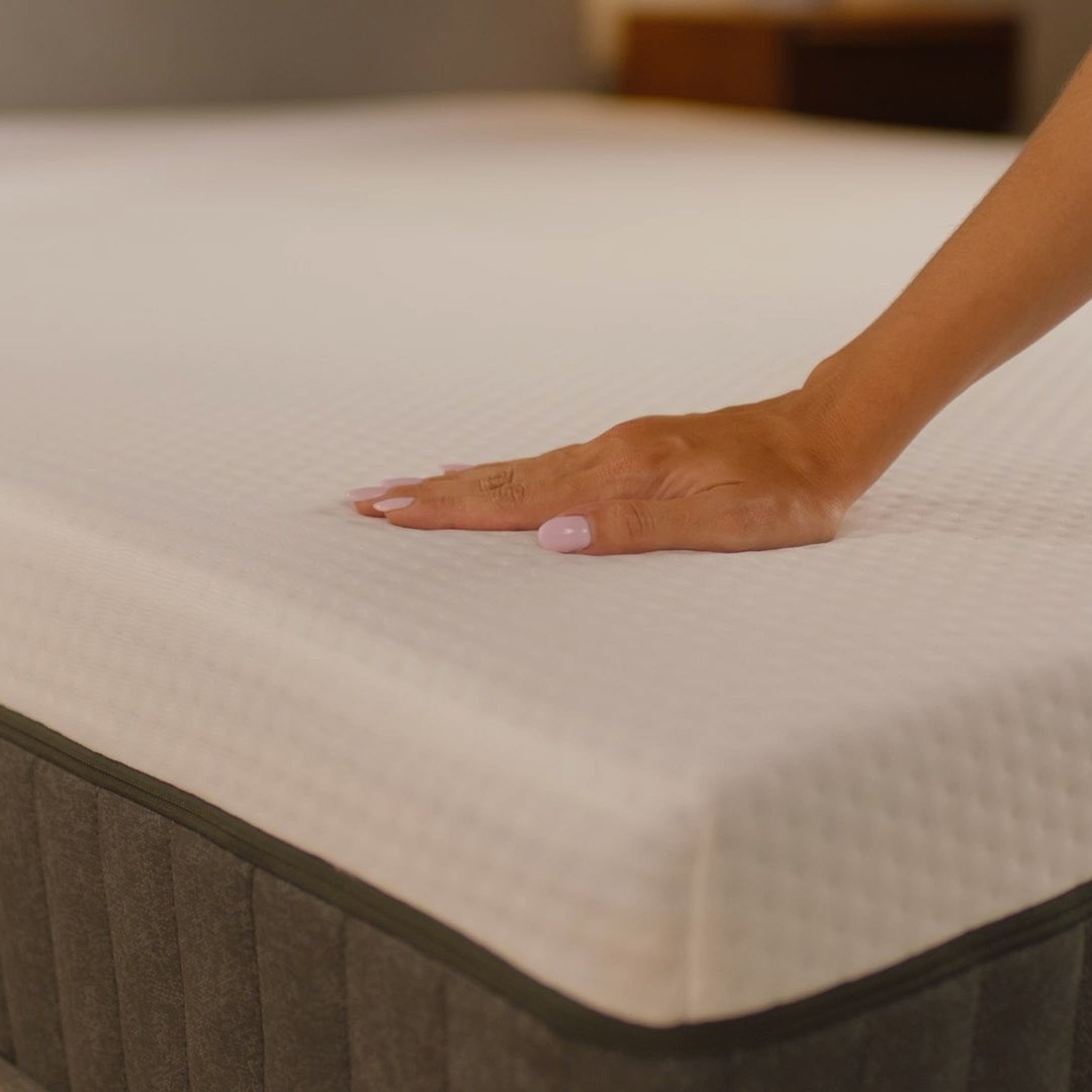 Person pressing the mattress surface to show its feel.