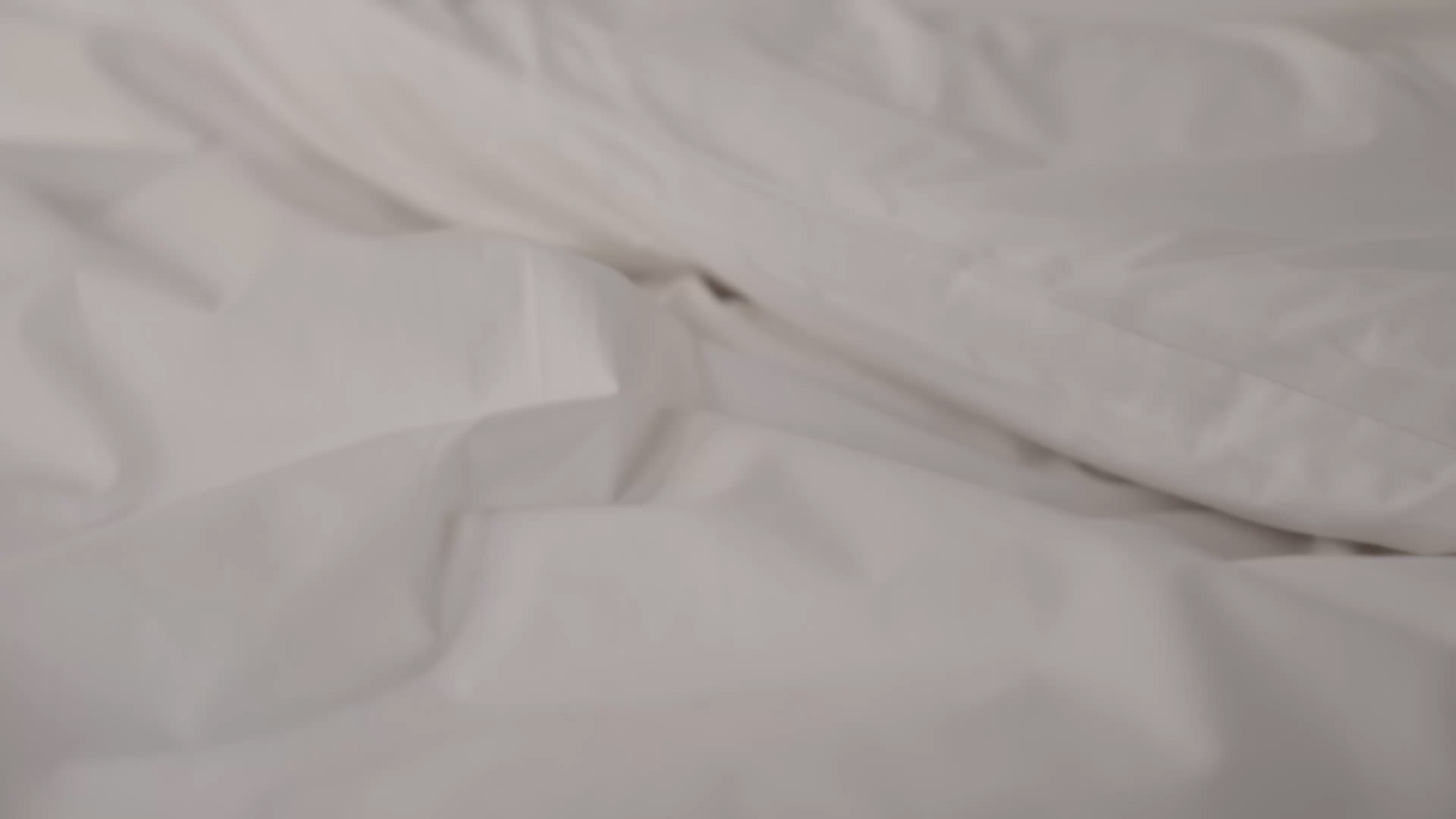 Close-up of bed linen fabric texture with soft folds.