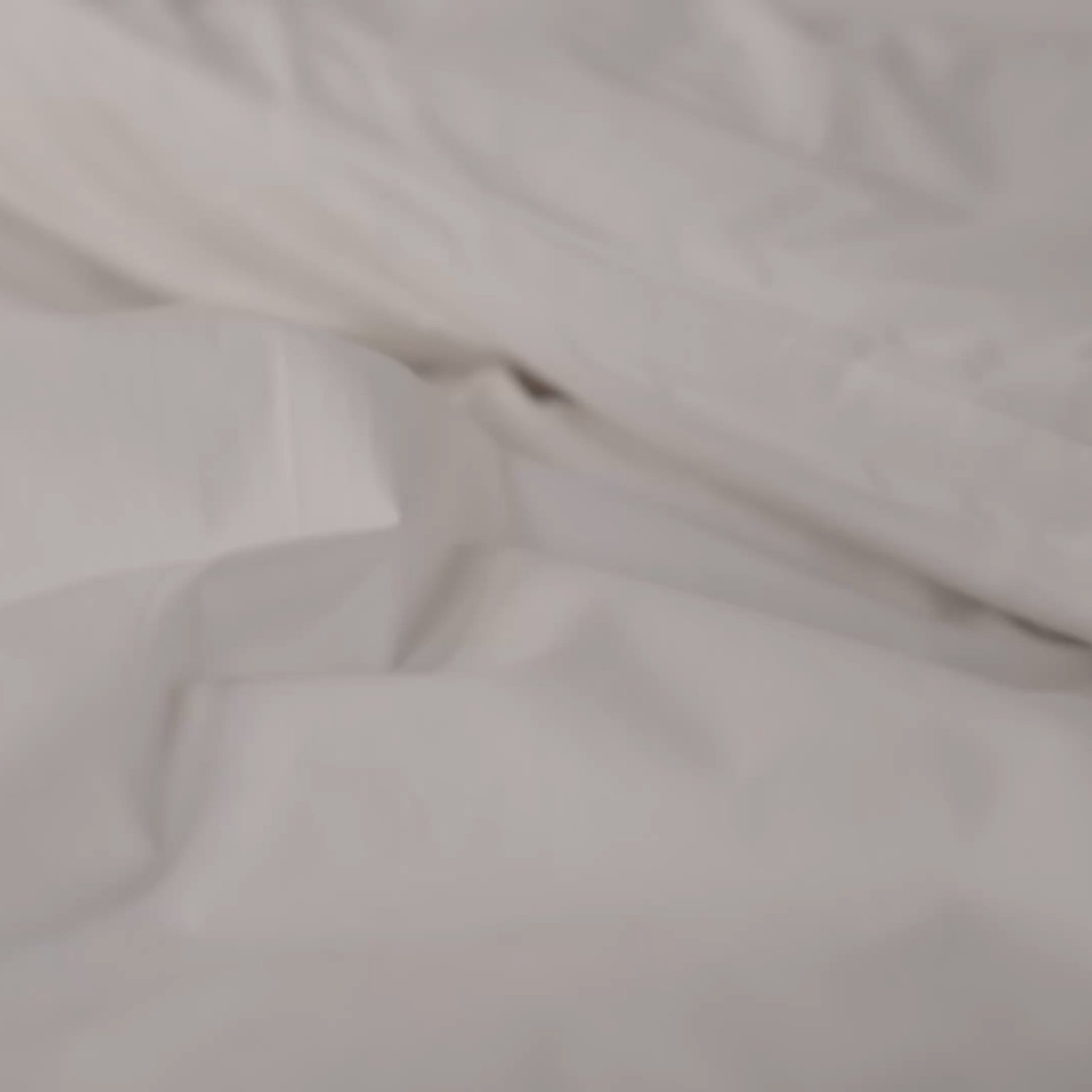 Close-up of bed linen fabric texture with soft folds.