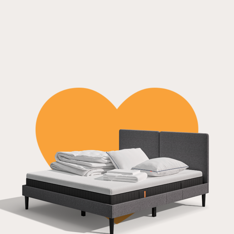 Lit moderne avec tête de lit grise et pieds noirs, recouvert de draps blancs. Deux oreillers blancs et une pile de linge plié sont posés sur le matelas. Arrière-plan beige avec une forme orange abstraite.