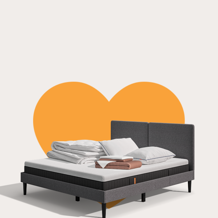 Lit moderne avec tête de lit grise et pieds noirs, recouvert de draps blancs. Deux oreillers blancs et une pile de linge plié sont posés sur le matelas. Arrière-plan beige avec une forme orange abstraite.