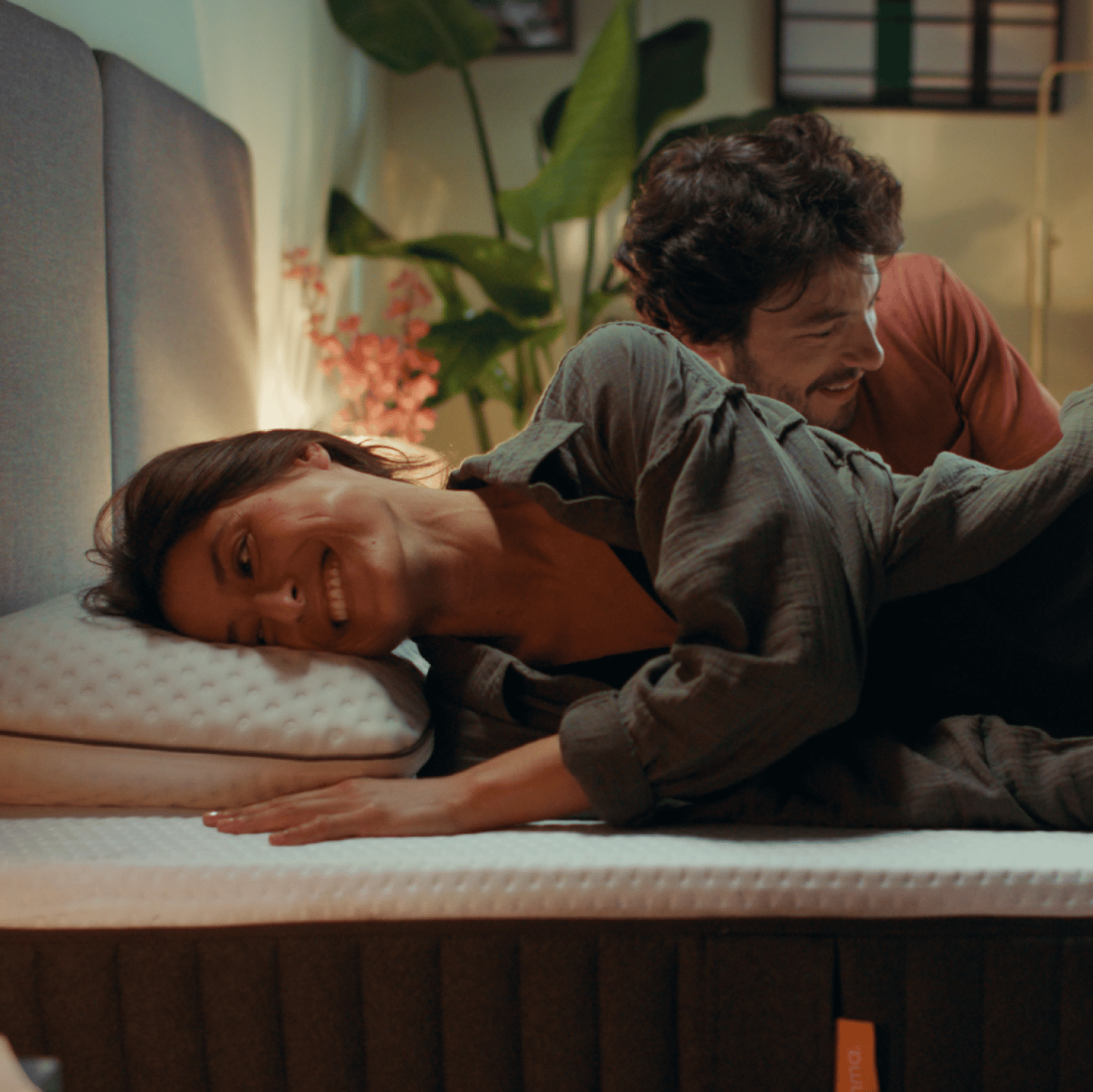 Paar liegt lächelnd gemeinsam auf einem Bett.