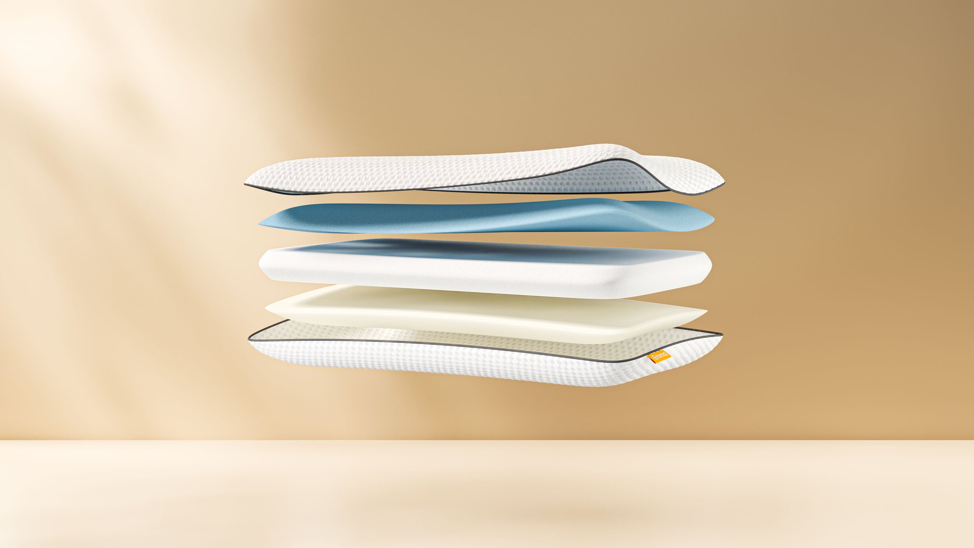 Doorsnede van Serta-kussen met zes lagen schuim (wit, blauw, wit, beige, wit, wit) en oranje merklabel; geribbeld oppervlak boven- en onderaan.