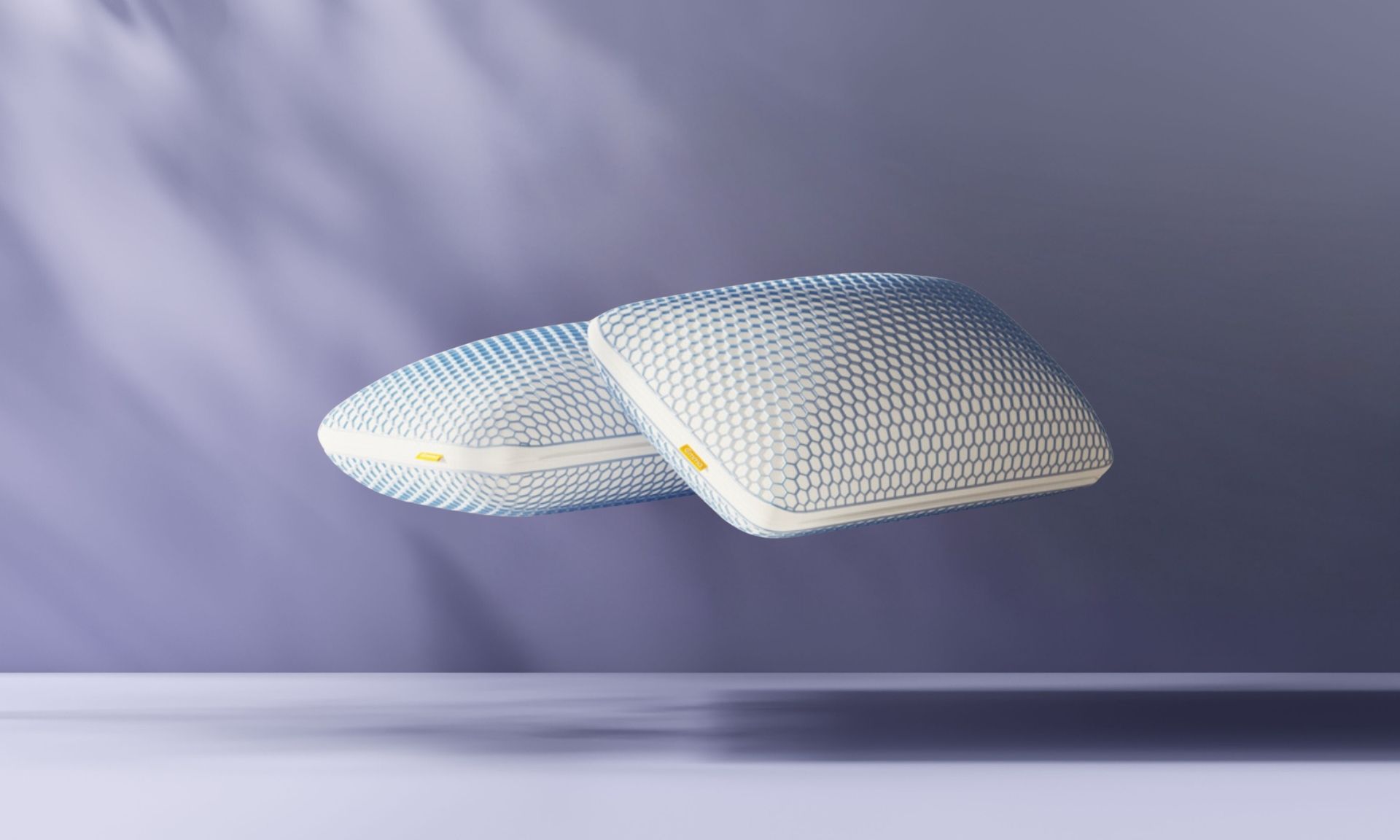 Duas almofadas Emma Microfibra Zero Gravity empilhadas sobre fundo azul