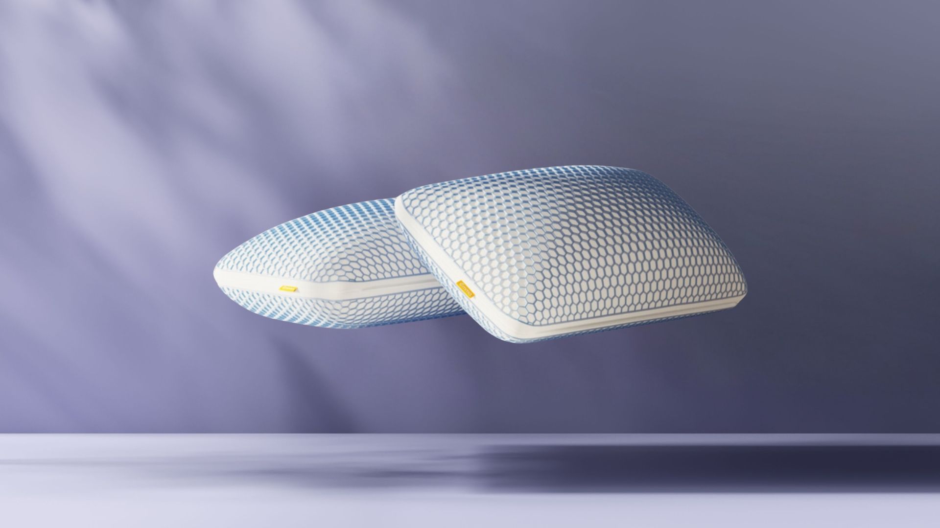 Duas almofadas Emma Microfibra Zero Gravity empilhadas sobre fundo azul