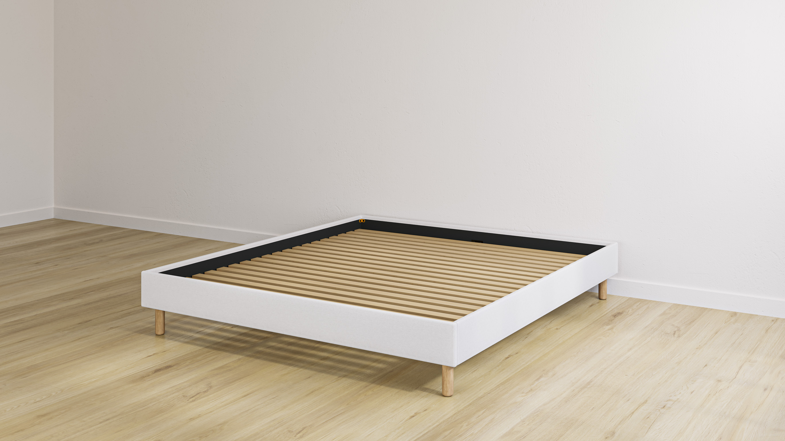Beige bedframe met houten lattenbodem in een lege kamer met lichte houten vloer.