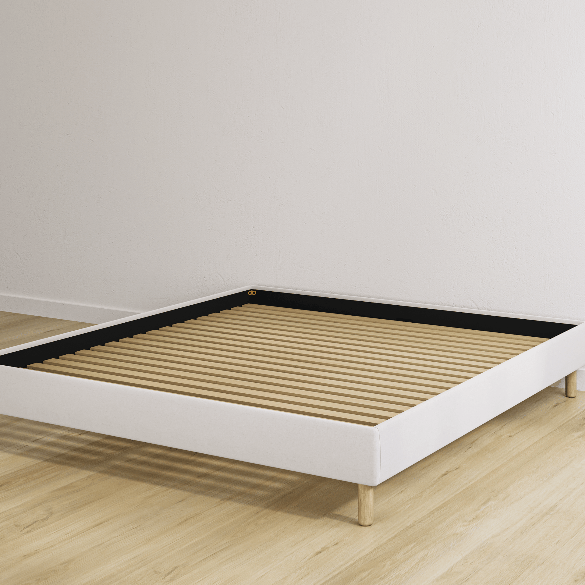 Beige bedframe met houten lattenbodem in een lege kamer met lichte houten vloer.