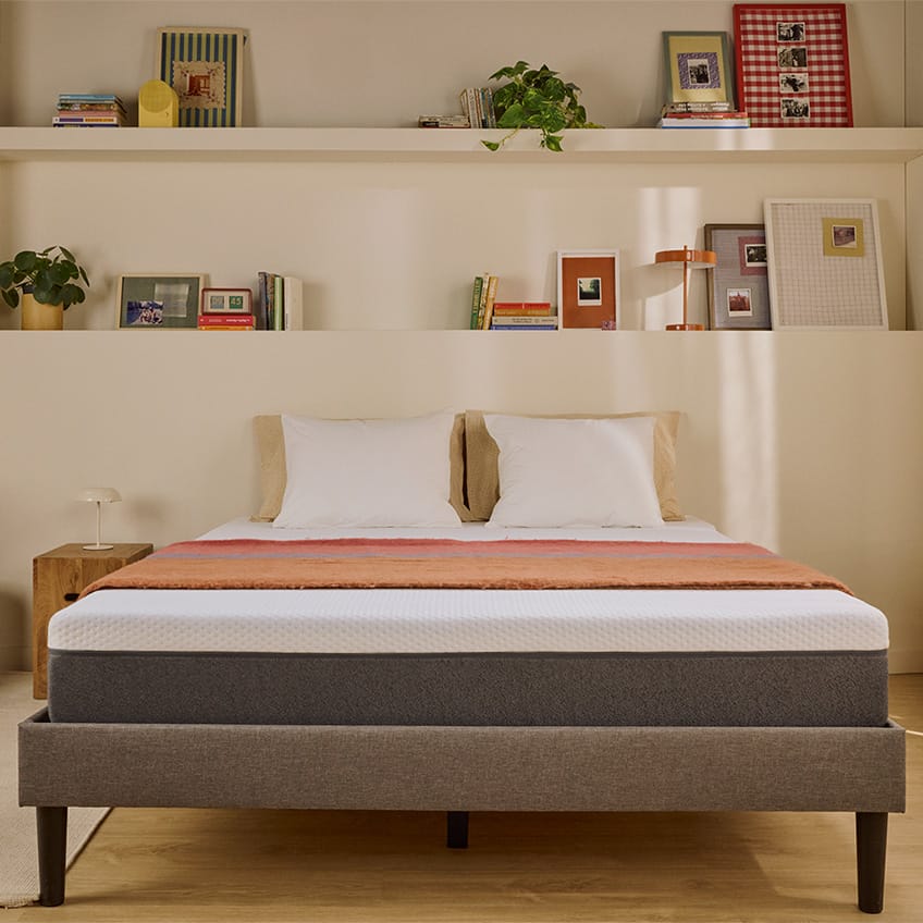 Colchão Emma branco sobre uma cama estofada.