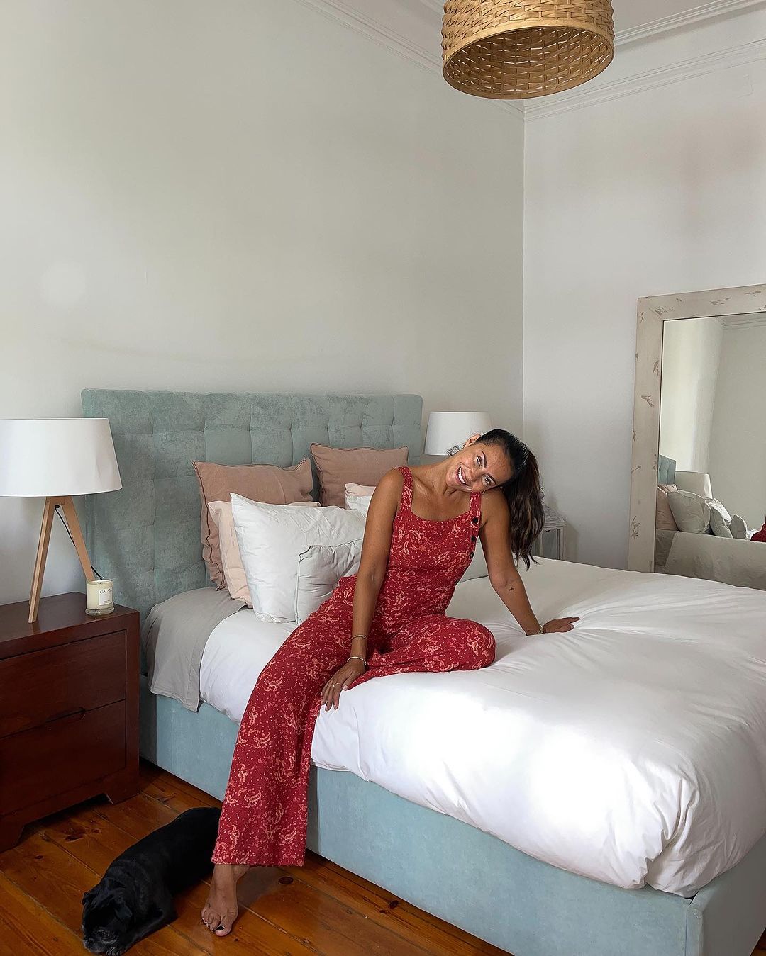 Mulher sentada à beira da cama num colchão Emma e um cão no chão