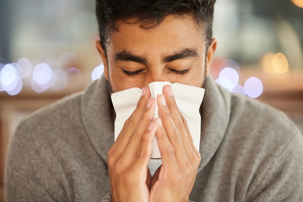 chico con alergia se suena la nariz con un pañuelo blanco