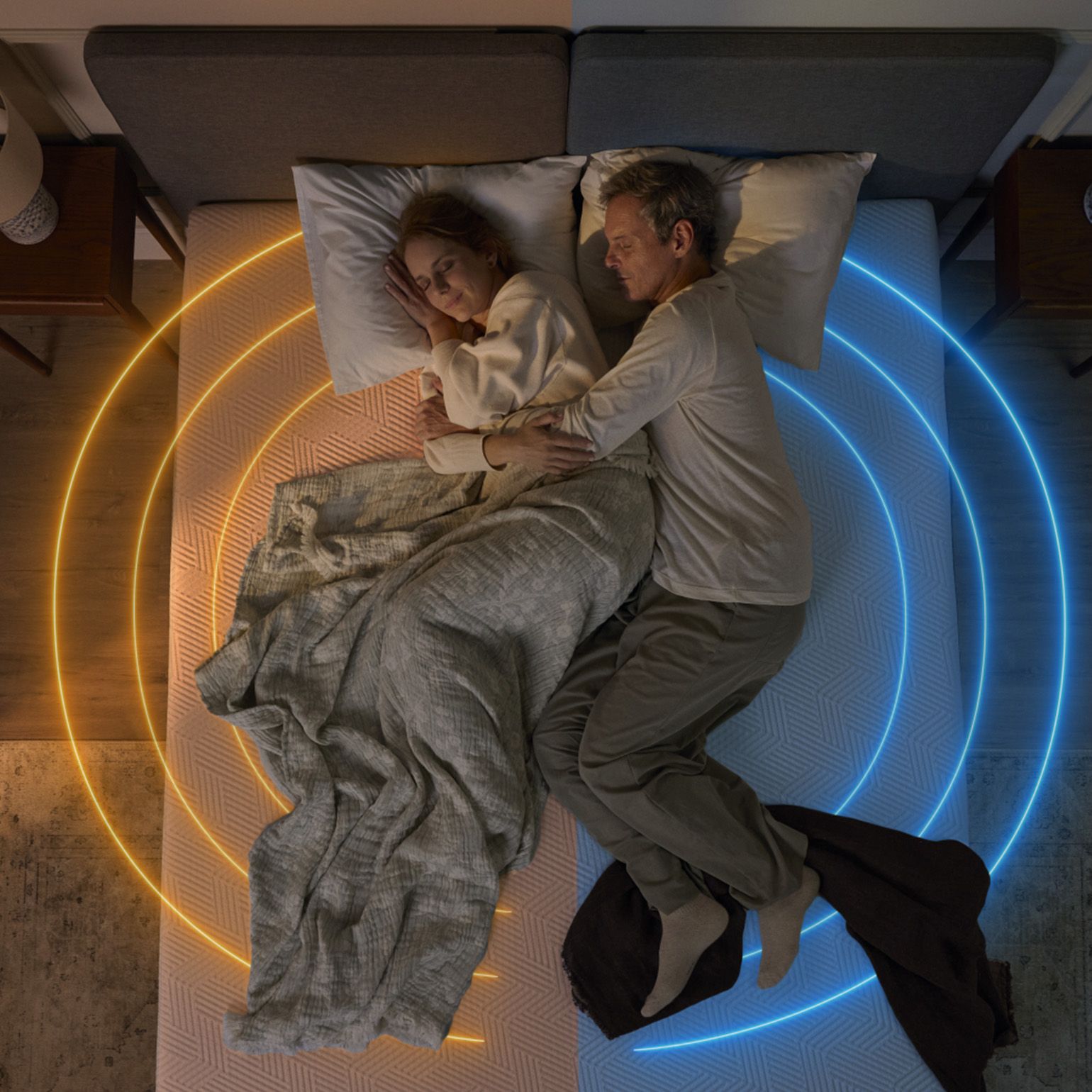 Un couple endormi sur un matelas, avec un éclairage tamisé de chaque côté.