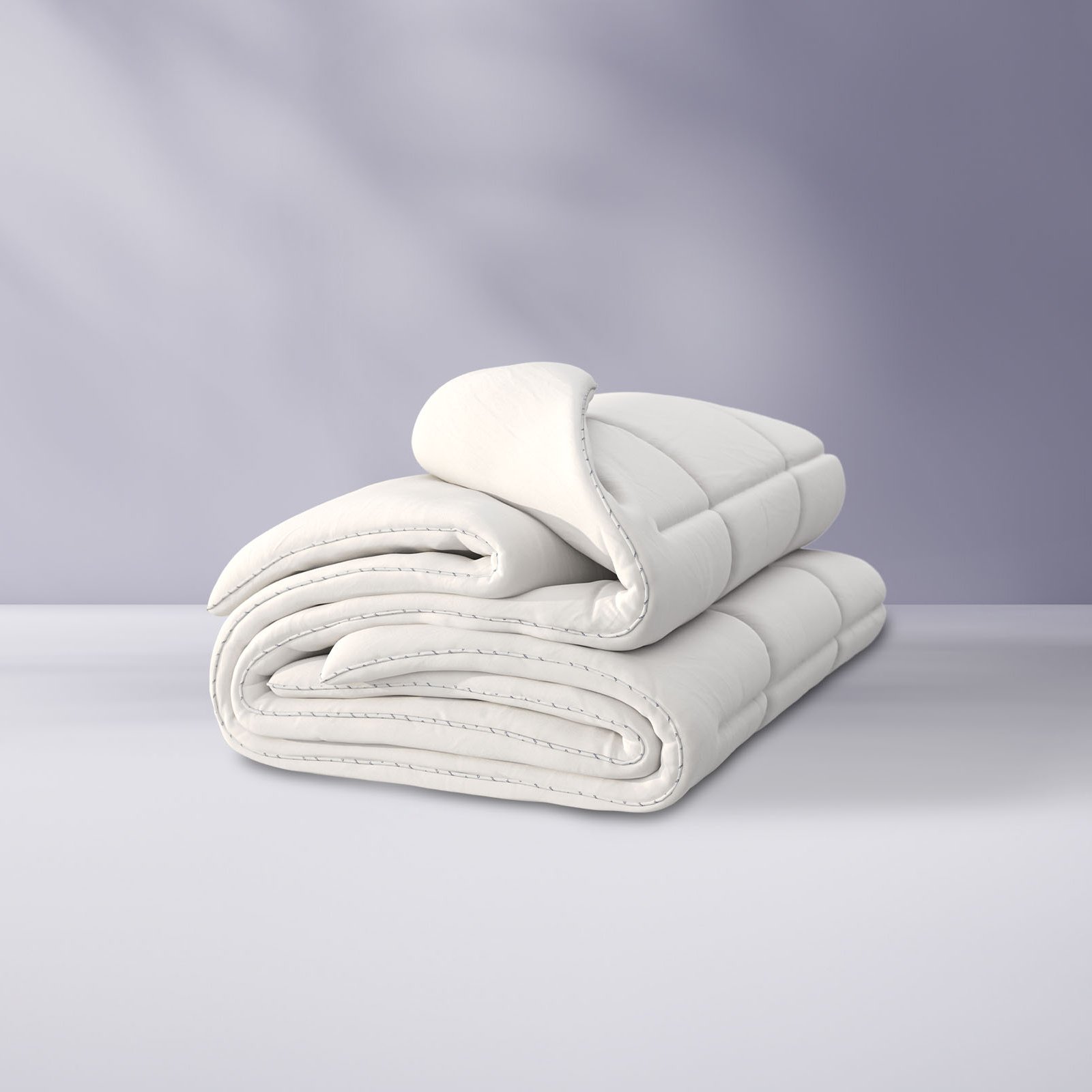 Couette pliée sur un fond violet clair.
