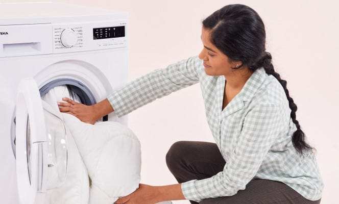 Frau neben Waschmaschine wäscht Emma-decke