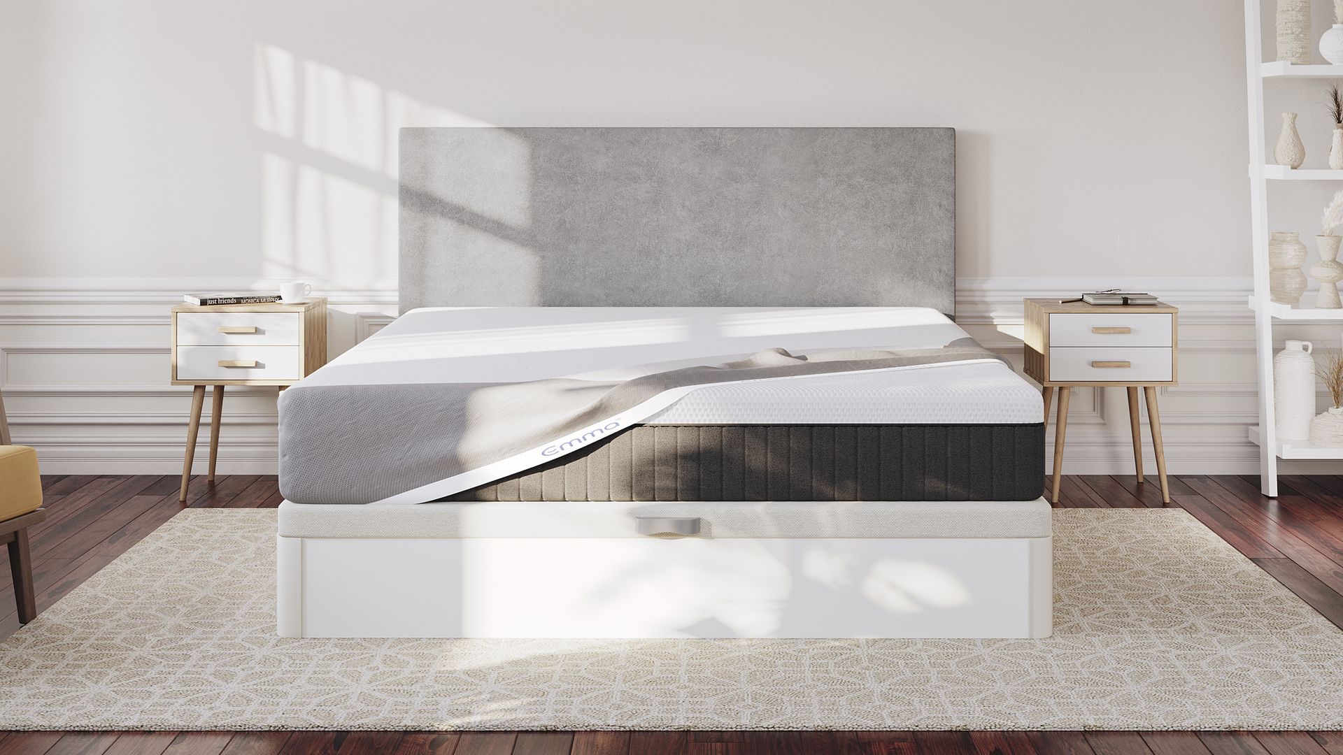Emma bed and and Emma Mattress Protector. The bed has a grey upholstered headboard, and natural light casting shadows across the mattress.